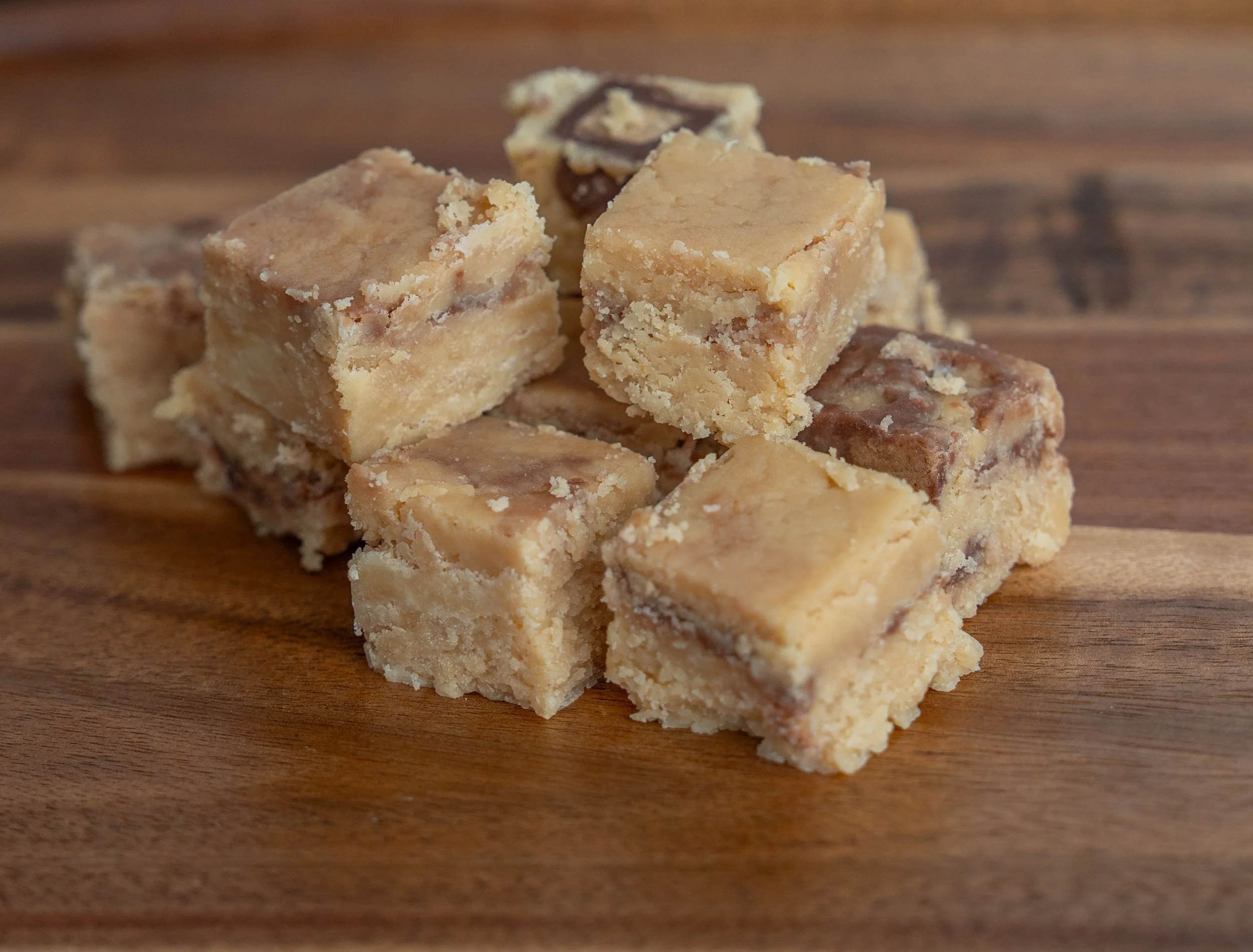 Close-up of a stack of blondie cookie bars with chocolate chunks on a wooden surface.