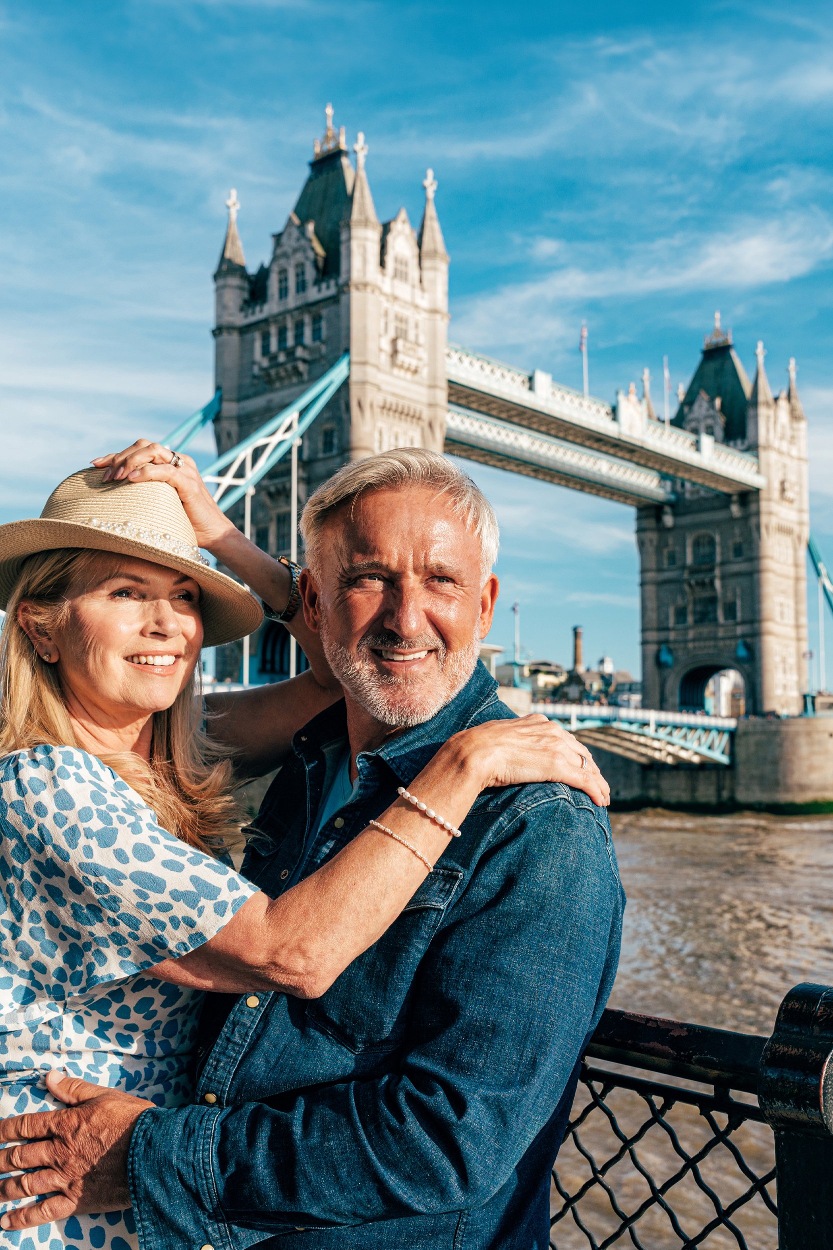 A middle-aged couple posing happily in front of the historic Tower Bridge in London during a bespoke city tour.