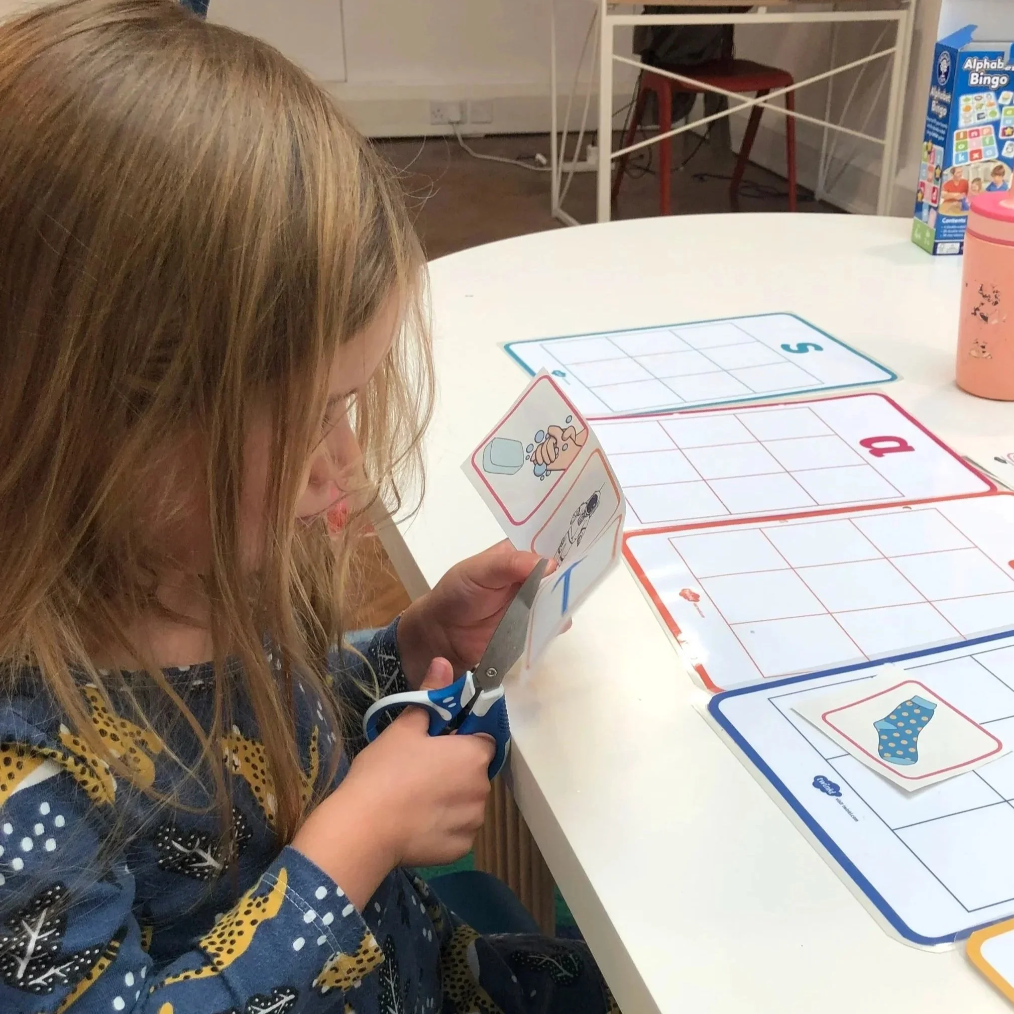 Young child cutting out images and letters during a creative tutoring session at The Study Studio, Parsons Green
