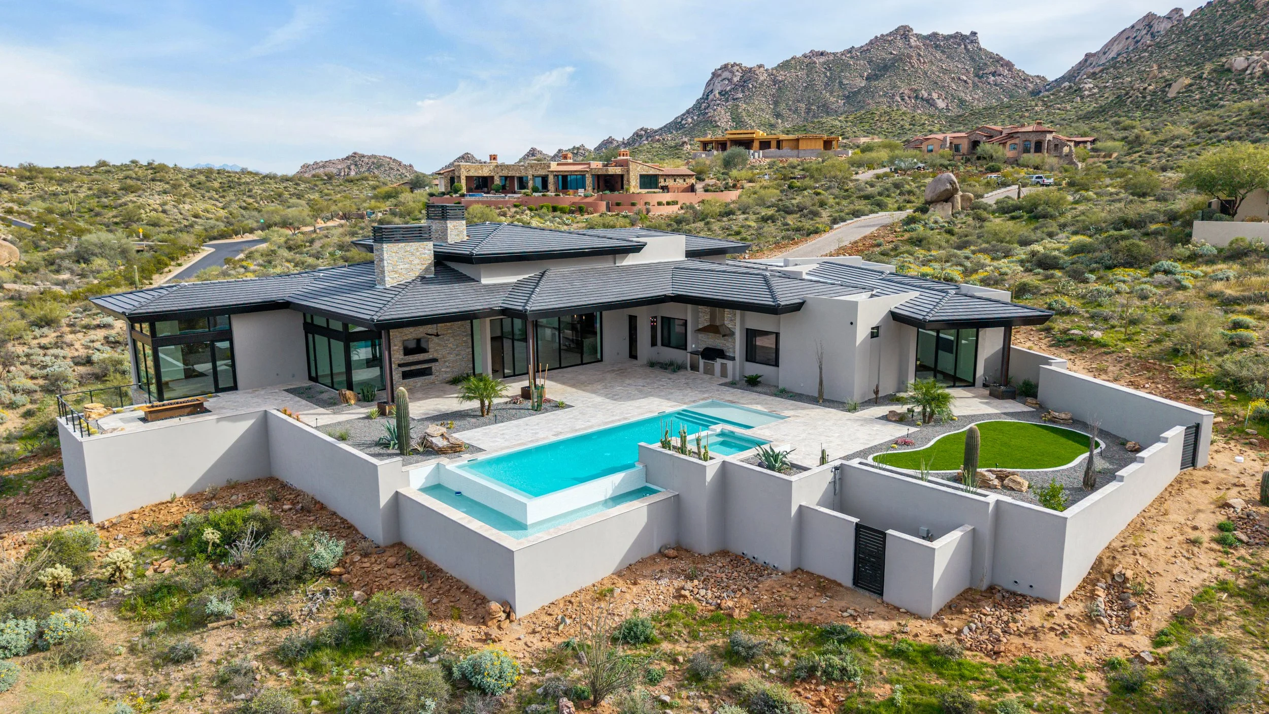 A modern house with a swimming pool and desert landscaping, nestled in a mountainous desert area.