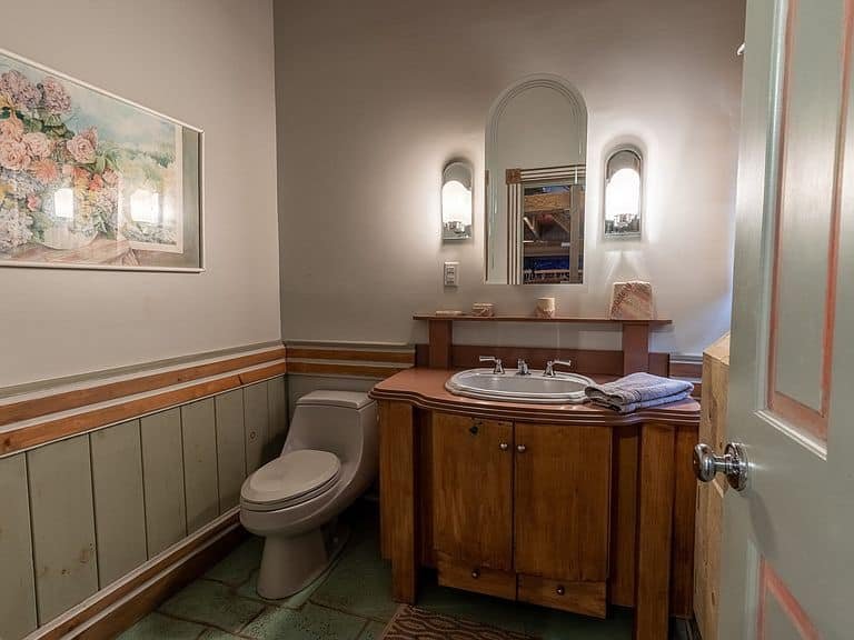Bathroom with a wooden vanity, small mirror, and toilet, in a cozy setting.