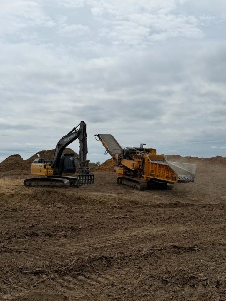 Construction site with two large excavator machines working on the dirt, under a cloudy sky.