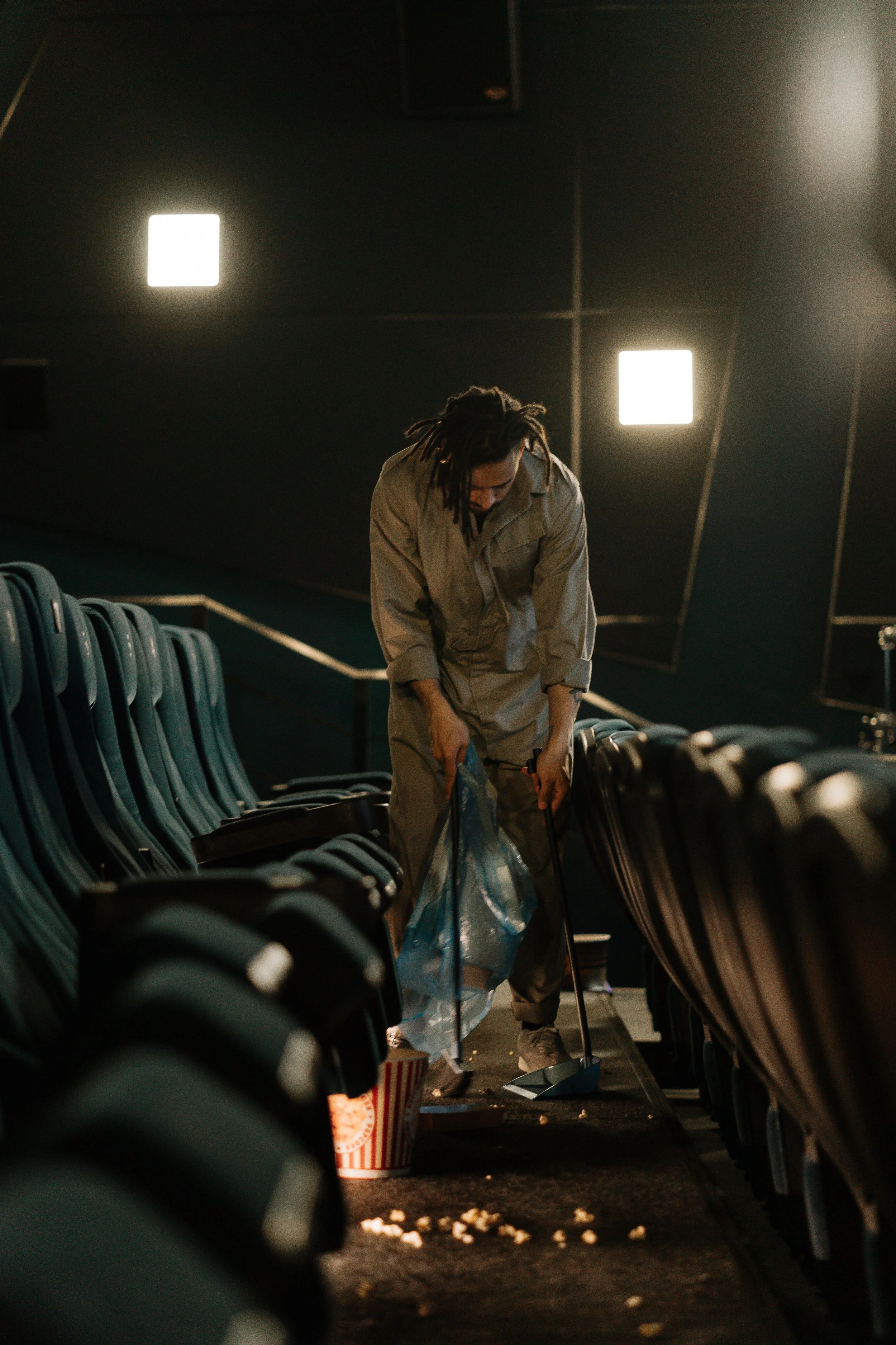 Facility maintenance professional cleaning a theater seating area.