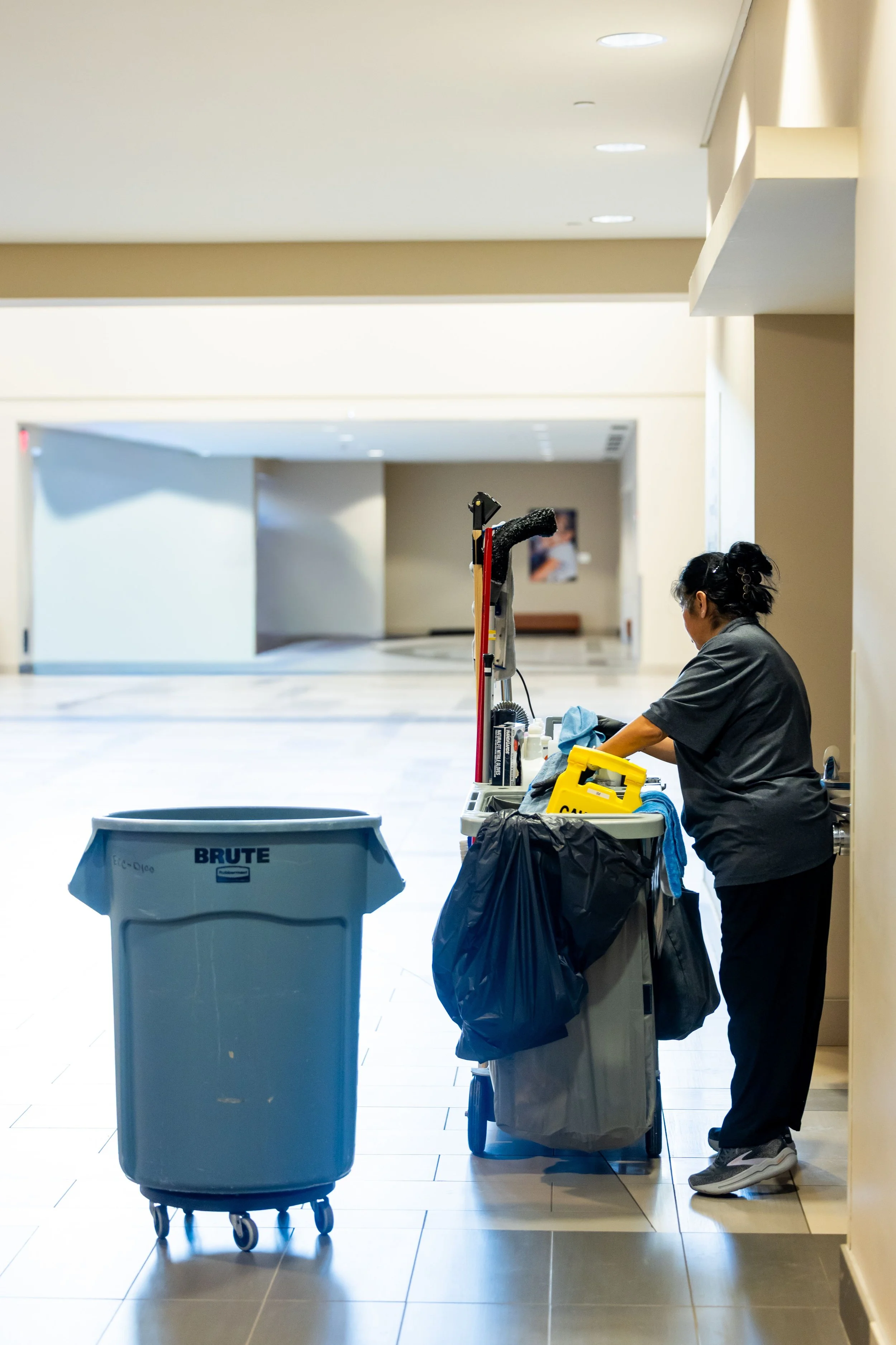 Professional janitorial cleaner with commercial cleaning equipment in a business facility.