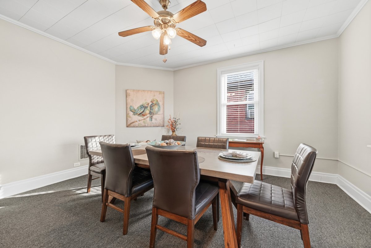 Dining room with a rectangular table, six chairs, a window, and a ceiling fan with lights.