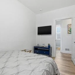 Bedroom with a bed, wall-mounted TV, and a blue furniture piece.