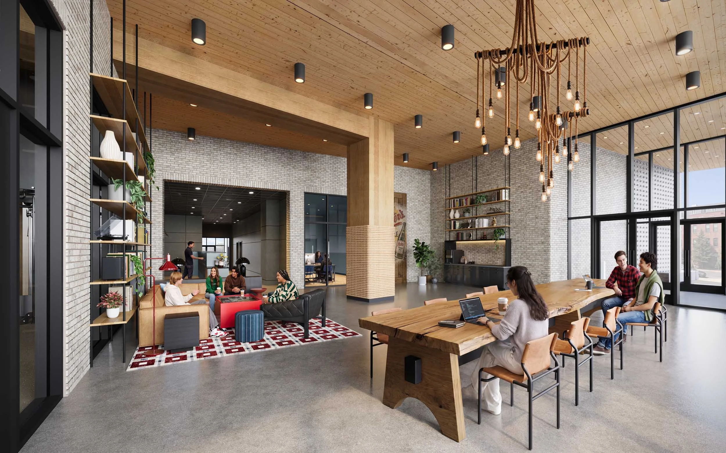 A modern, spacious coworking space with large windows, wood ceiling, exposed brick walls, and contemporary decor. Multiple groups of people are working and chatting at tables and sofas. There are plants, shelves, and a decorative chandelier made of ropes with bulbs.