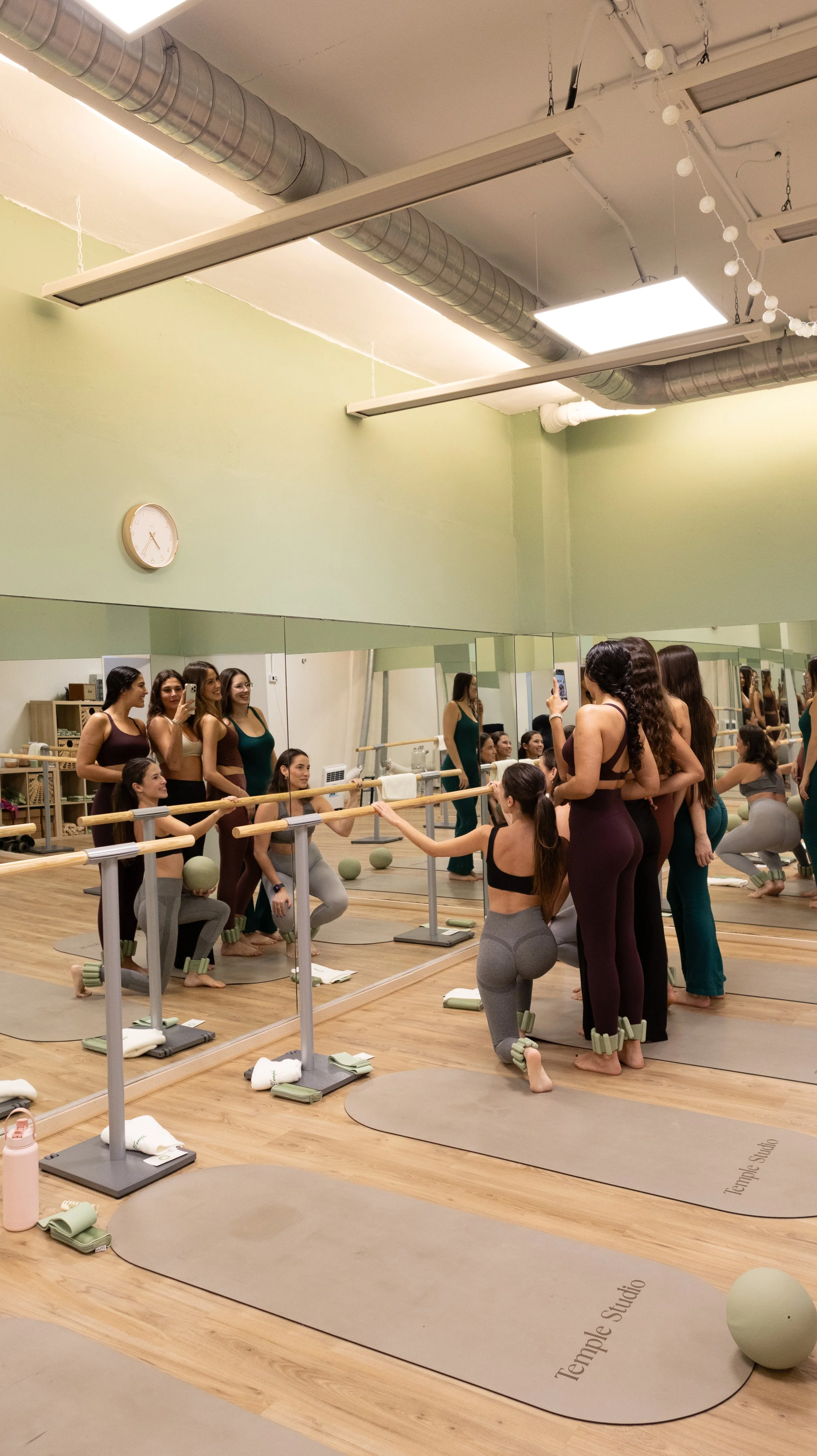 grupo de mujeres haciendo Pilates en un estudio con espejos, colchonetas y pelota medicinal