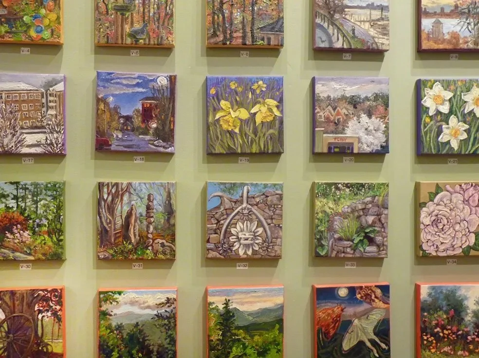 Gallery wall with various landscape and floral paintings arranged in rows.
