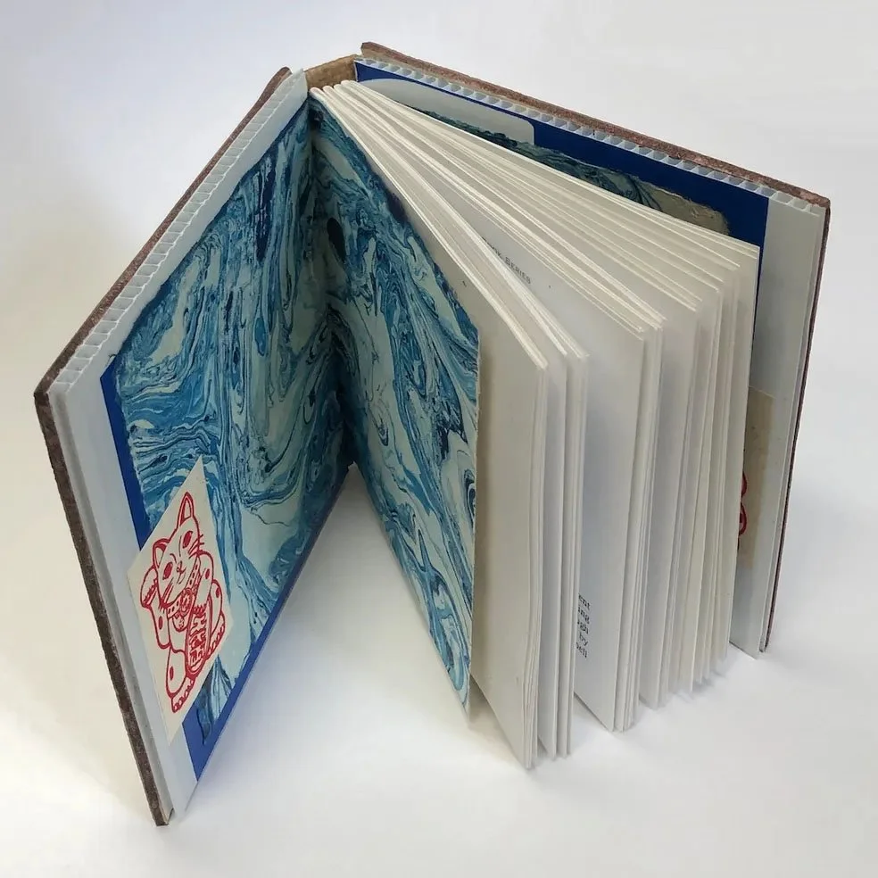 Open notebooks with marbled blue pages and a sticker of a cat with a fish.