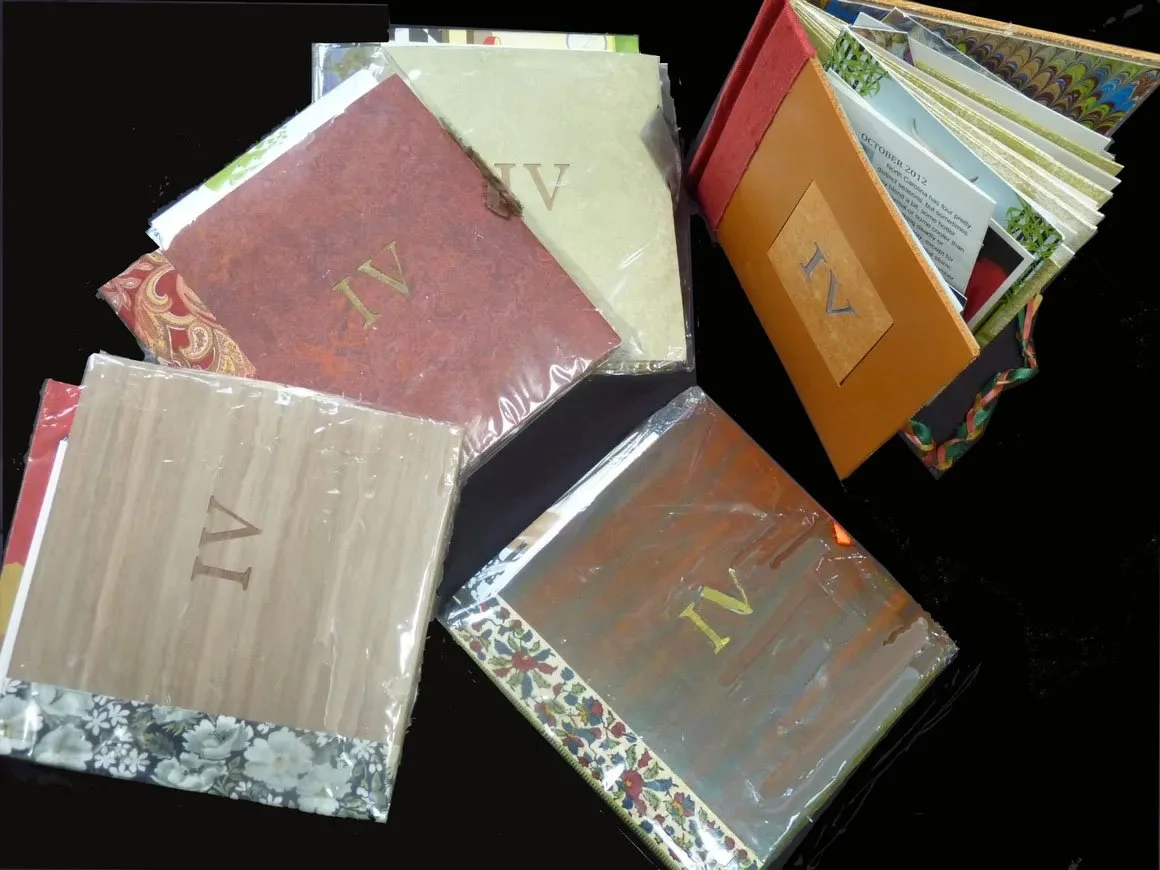 Handmade photo albums with acetate covers, each labeled with the letters 'A' and 'V', placed on a black surface.