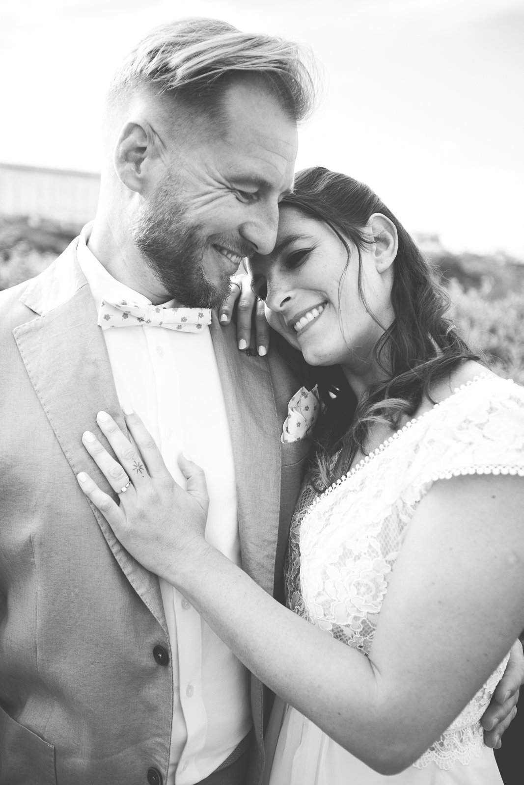 Un couple marié, un homme et une femme, sourient et sont très proches, l'air heureux dans une photo en noir et blanc.
