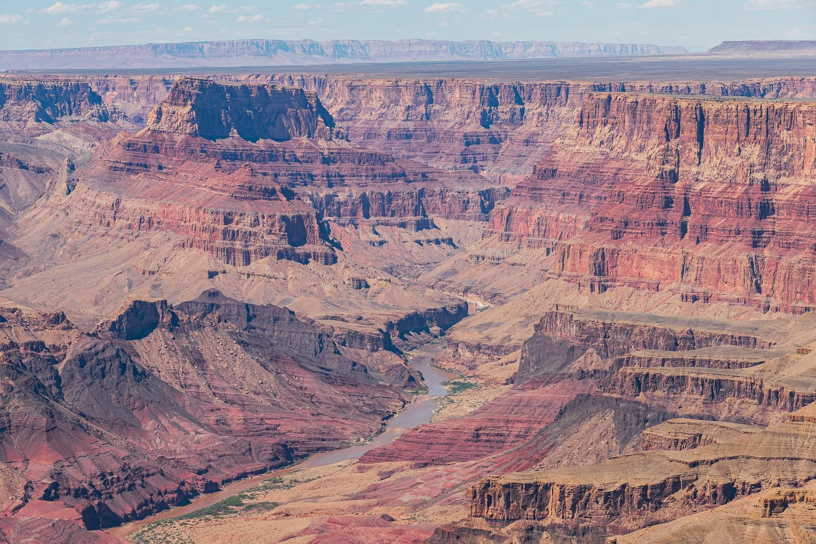 Cliché du Grand Canyon avec ses falaises, ses couches géologiques colorées et le Colorado River serpentant en bas.