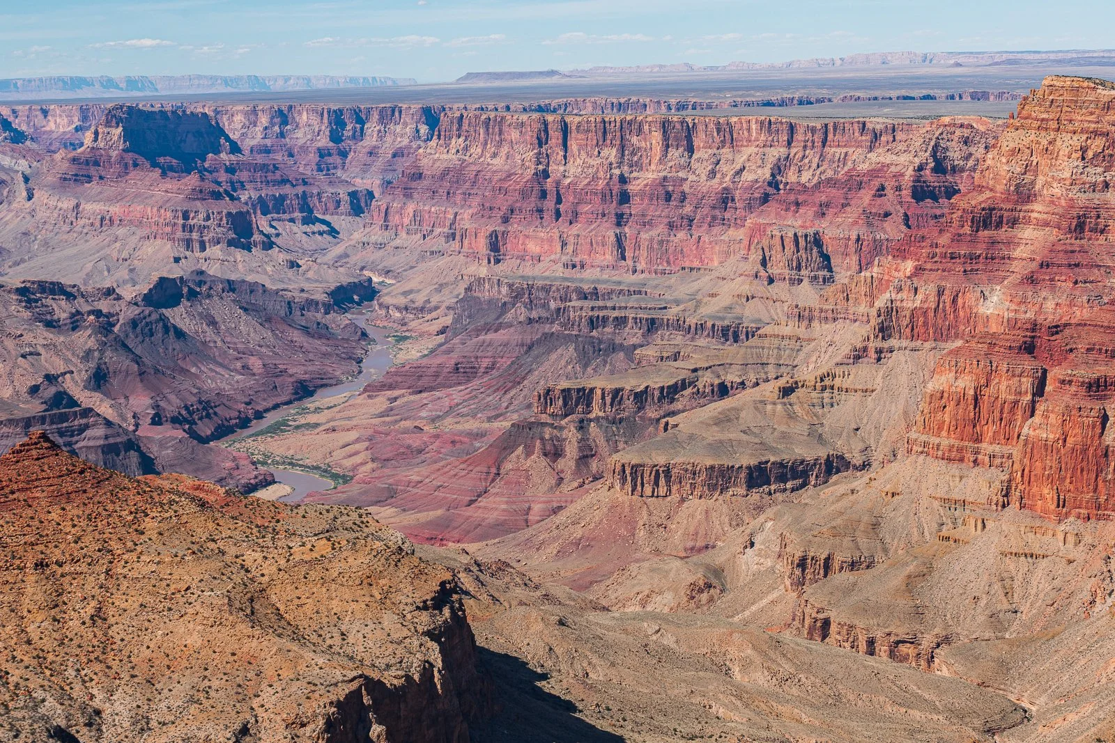 Vue aérienne du Grand Canyon avec ses formations rocheuses colorées et le Colorado qui serpente au fond.