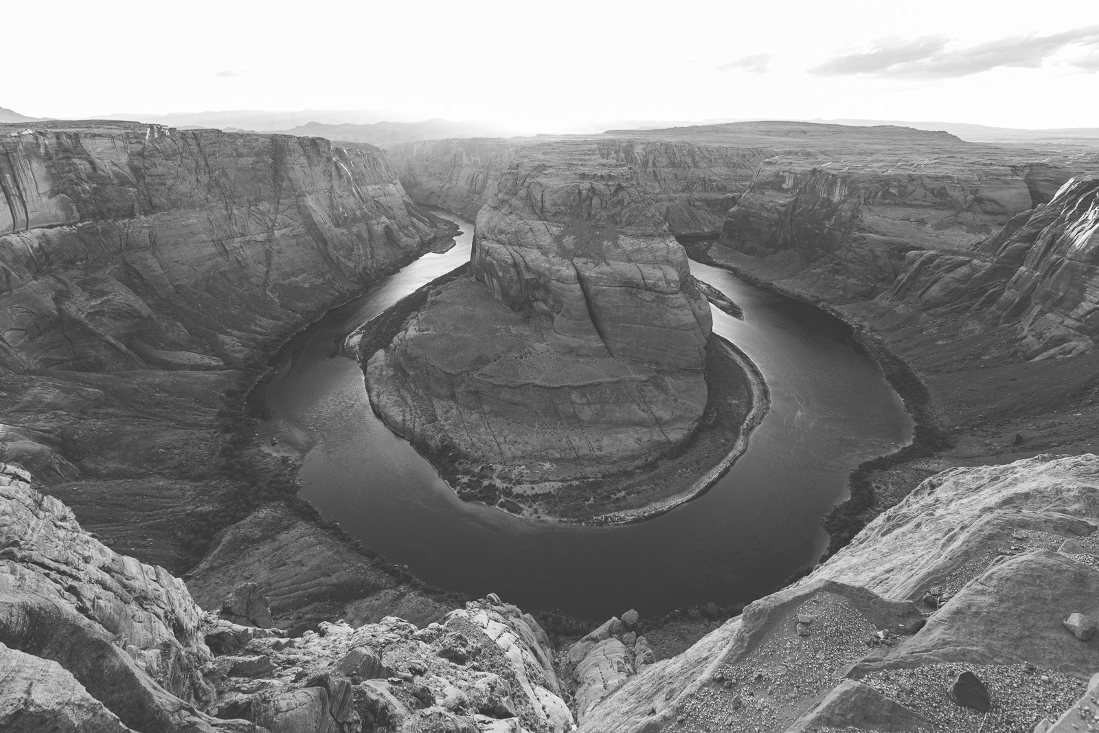 Une vue en noir et blanc du canyon de Horseshoe Bend avec la rivière serpentant autour d'une grande formation rocheuse centrale.