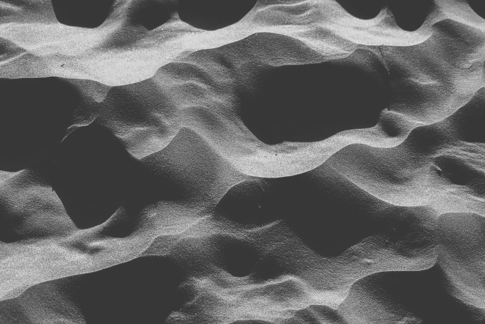 Sable fin et texturé avec des dépressions et des bosses. Obturation en noir et blanc.