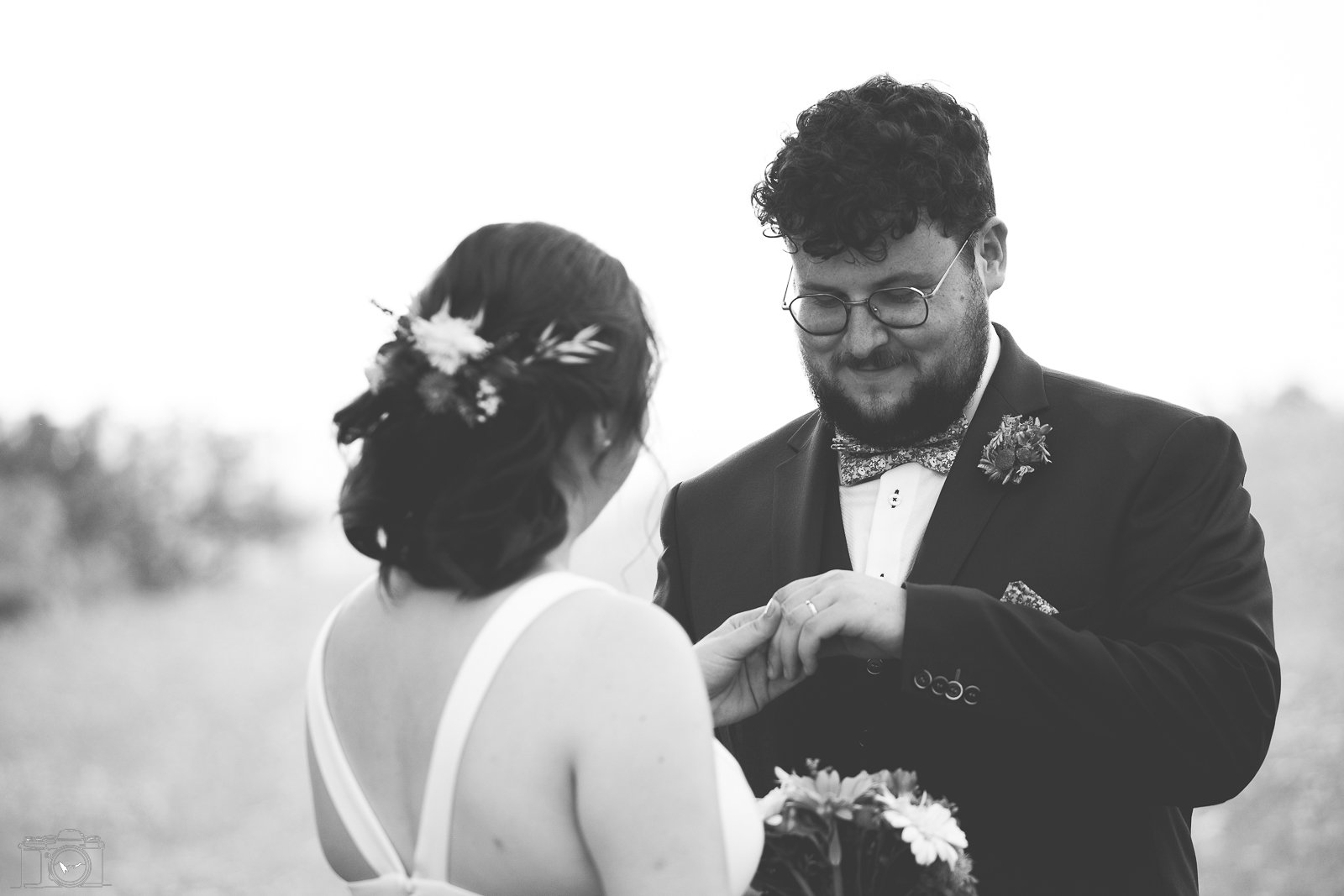 Un couple de mariés s'échangeant leurs alliances lors de leur mariage, en noir et blanc.