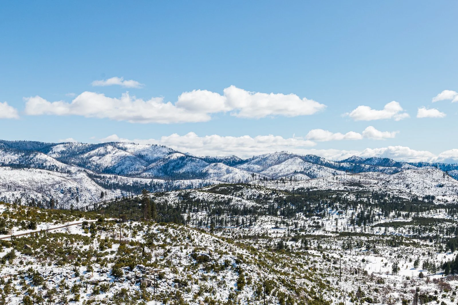 Paysage de montagnes enneigées avec ciel bleu et nuages blancs.