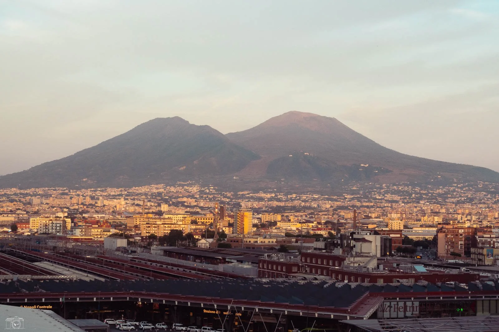 Une vue urbaine de Naples avec le Vésuve en arrière-plan au coucher du soleil.