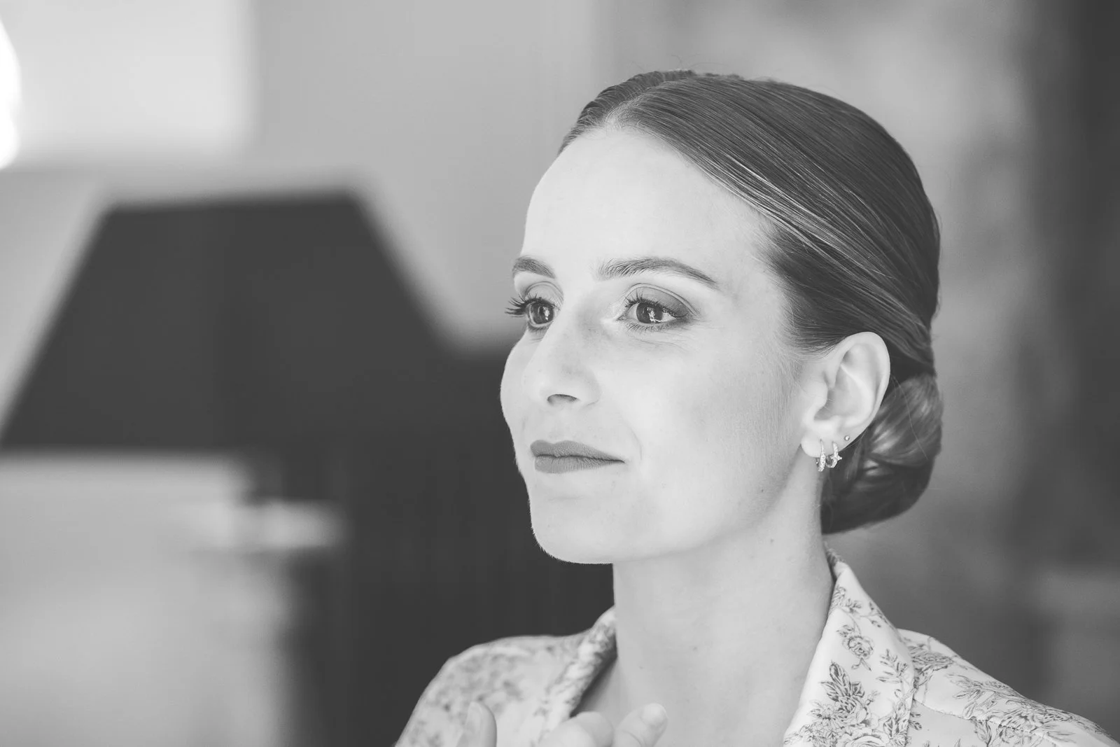 Portrait en noir et blanc d'une femme regardant vers la gauche, avec une coiffure élégante et des boucles d'oreilles.