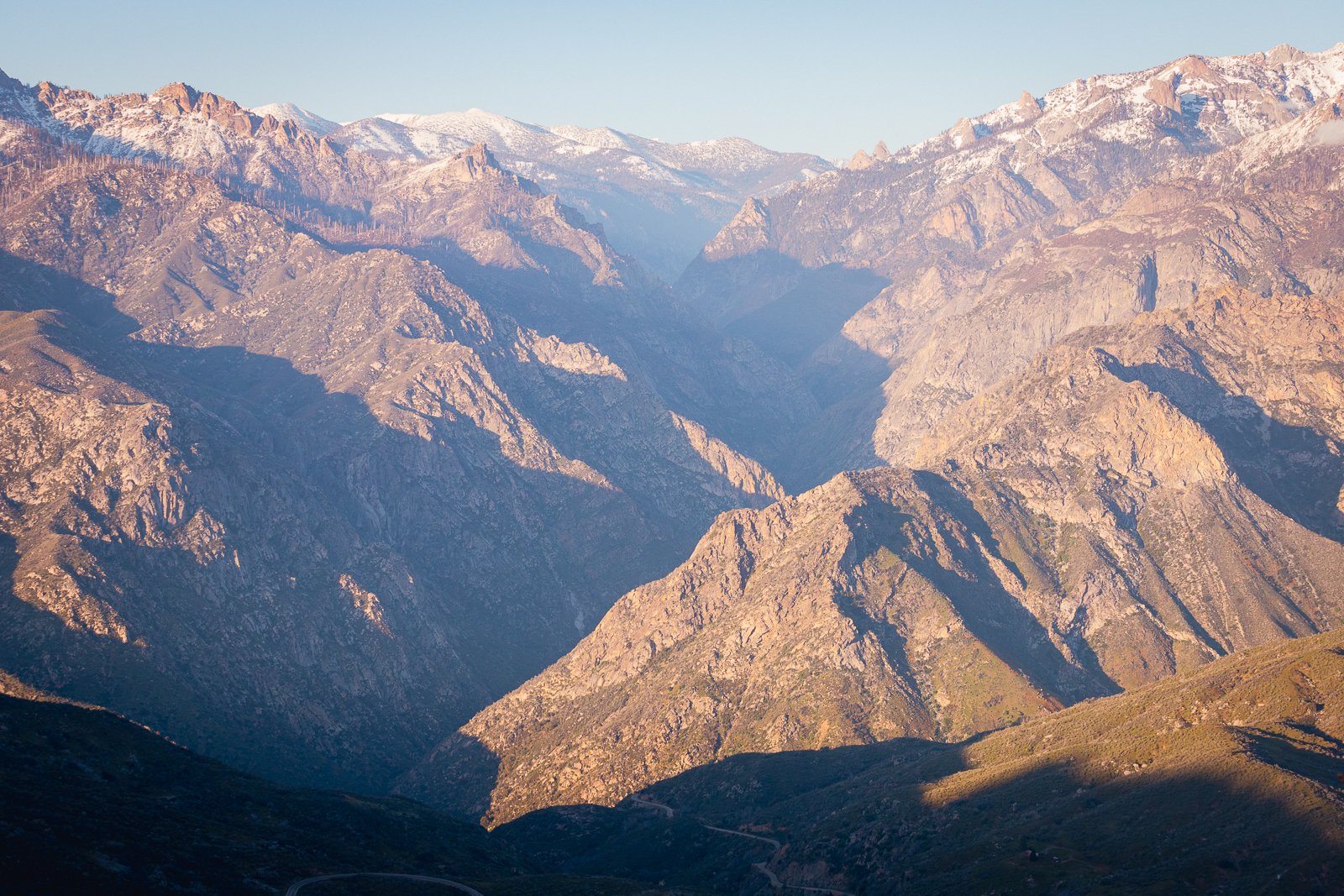 Chaîne de montagnes avec des sommets enneigés et des vallées rocheuses, sous un ciel clair.