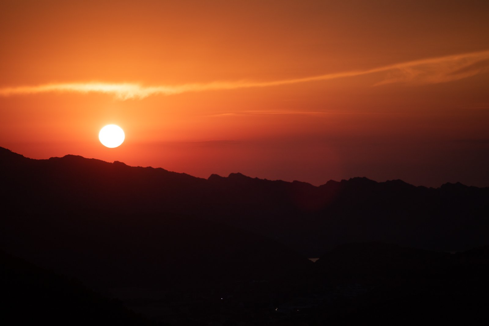 Coucher de soleil sur des montagnes avec ciel orange et nuages.