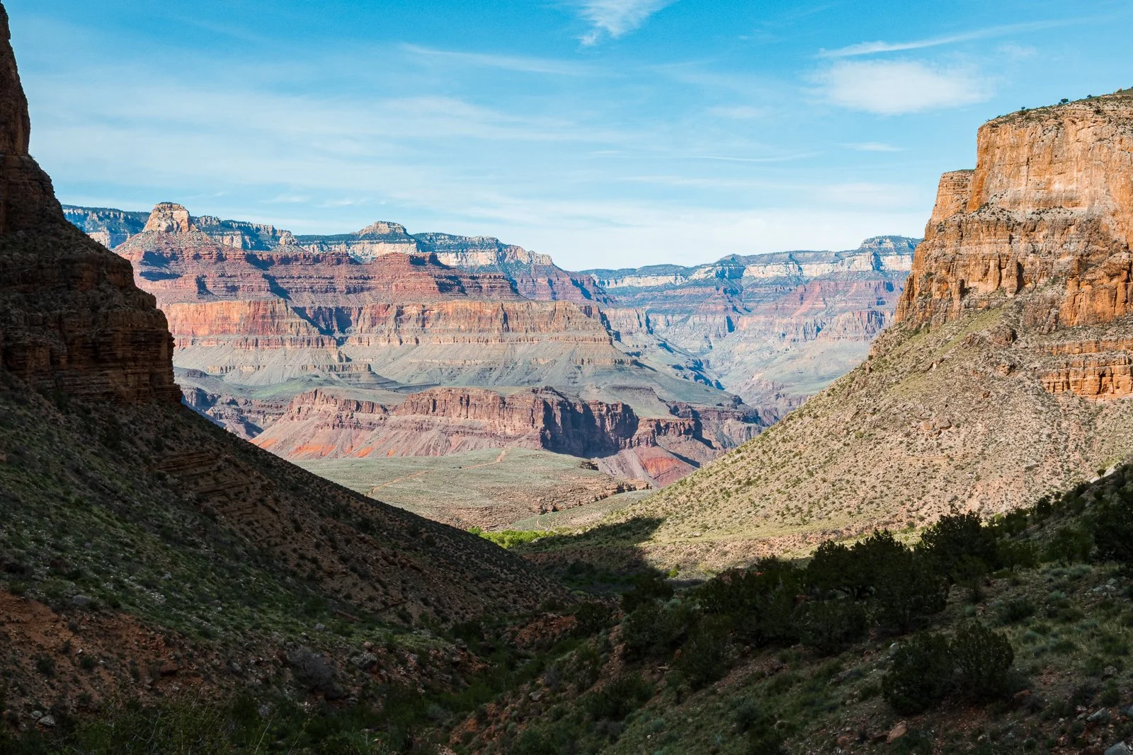 Vue panoramique du Grand Canyon avec ses formations rocheuses colorées et le ciel bleu au-dessus.