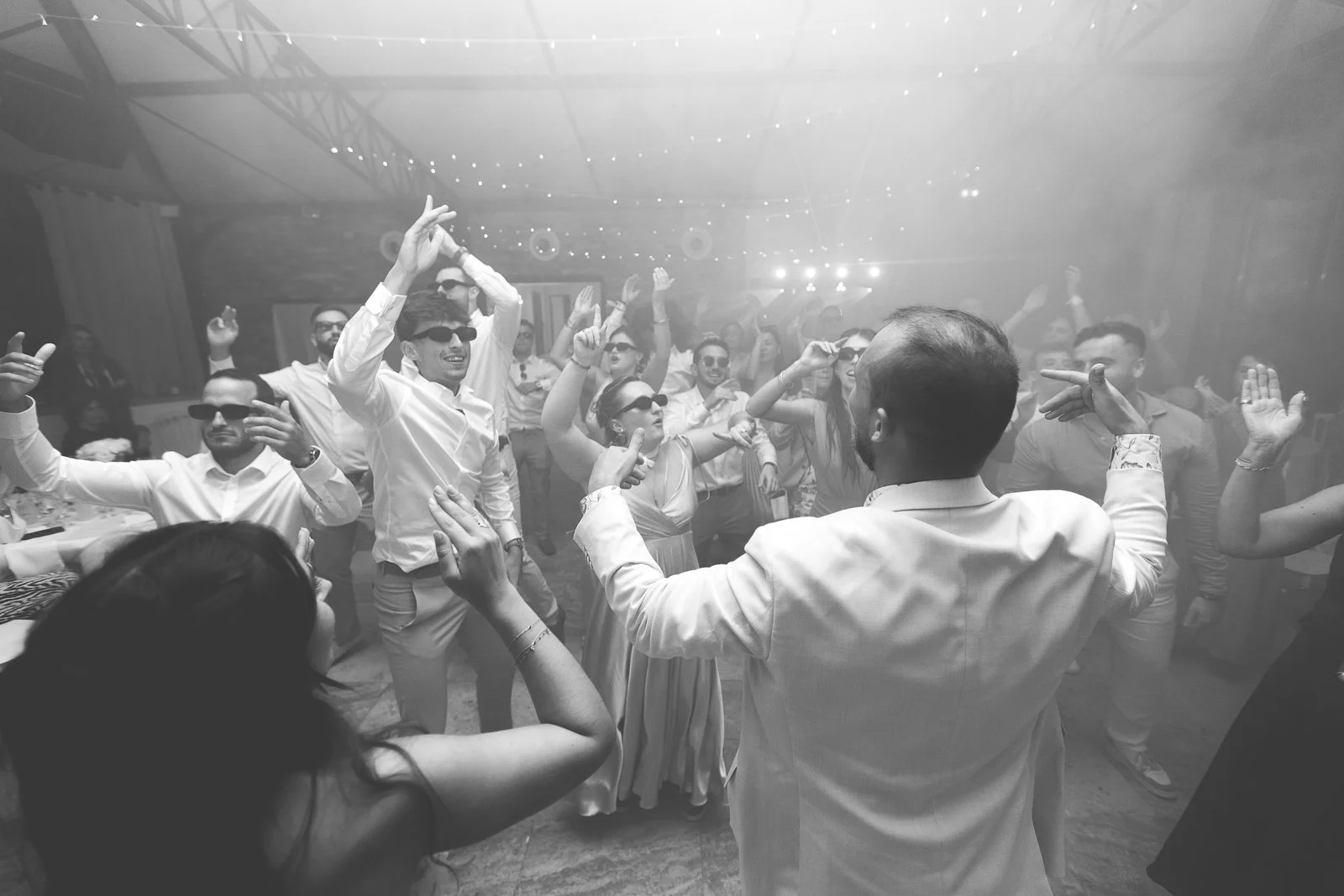 Groupe de personnes dansant et s'amusant lors d'une fête ou d'un événement social, avec des lumières et un environnement festif.