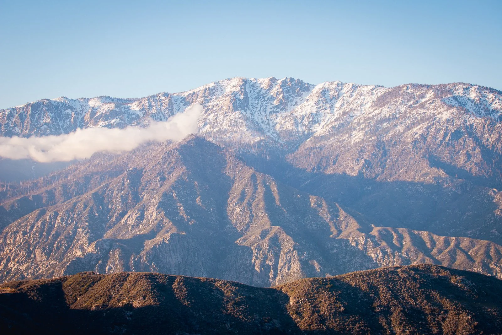 Montagnes rocheuses avec pics enneigés sous un ciel clair.