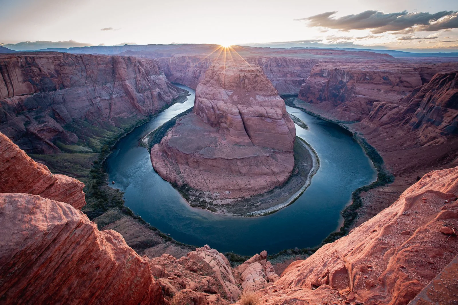 Canyon du Colorado avec la rivière serpentant autour d'une formation rocheuse en forme de île au coucher du soleil.