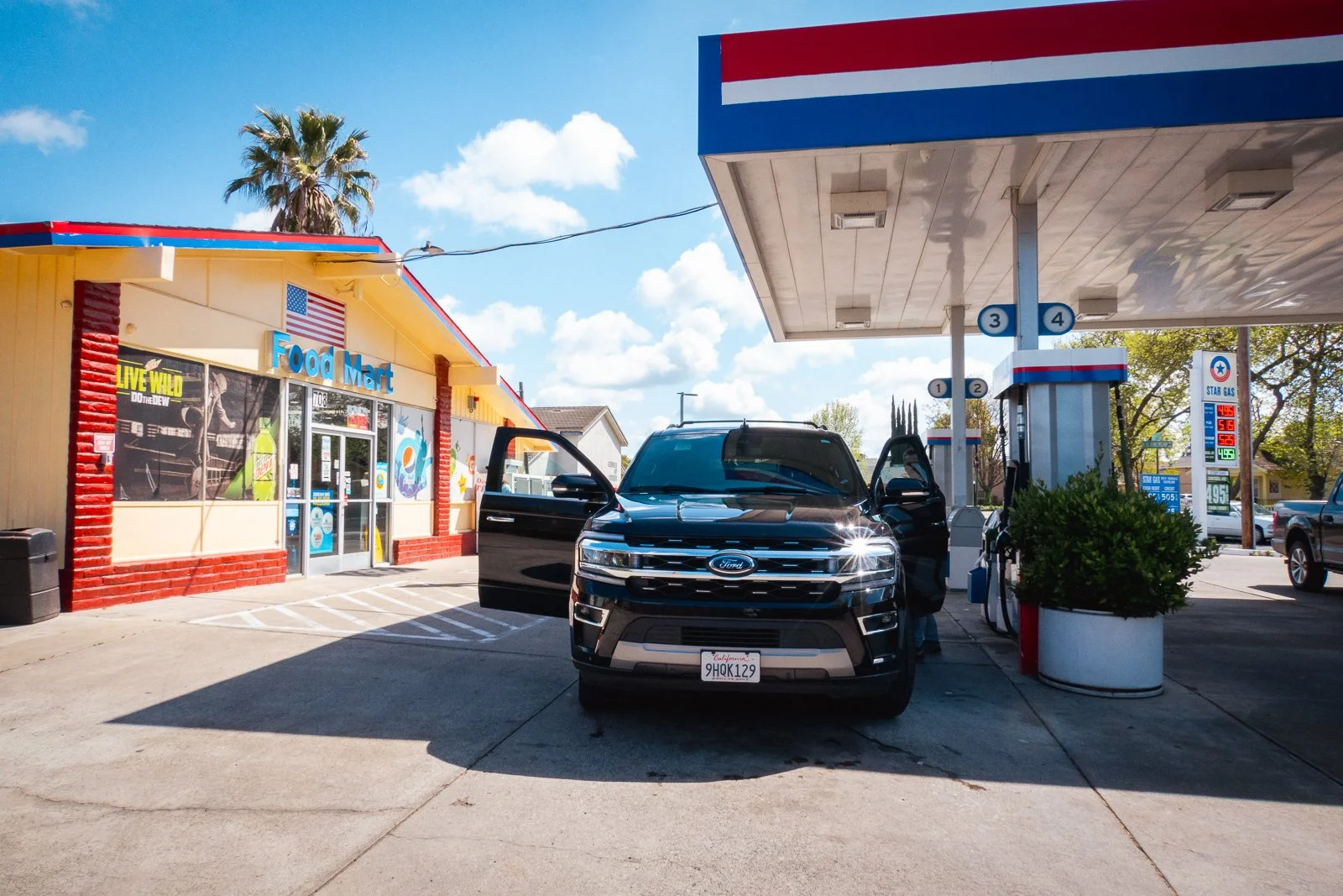 Une station-service avec une voiture noire Ford garée, près de la station essence, en face d'un magasin alimenté aux États-Unis.