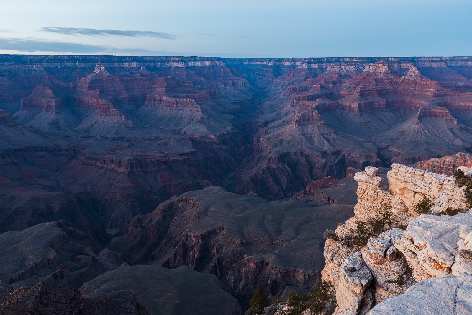 Canyon du Grand Canyon au crépuscule avec des formations rocheuses et un ciel partiellement nuageux.