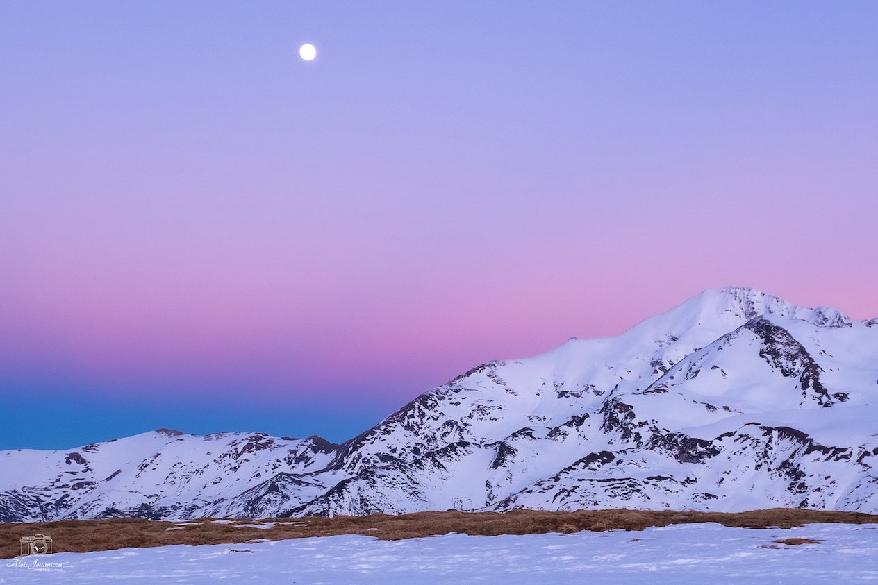 Montagnes enneigées sous un ciel pastel avec la pleine lune