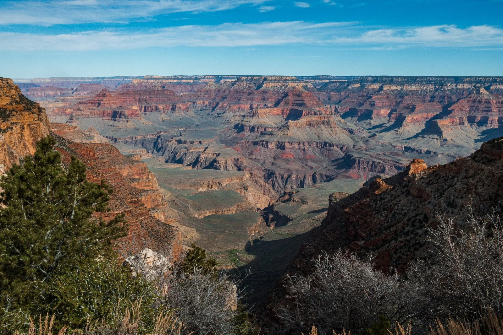 Vue du Grand Canyon avec des formations rocheuses et un ciel bleu.