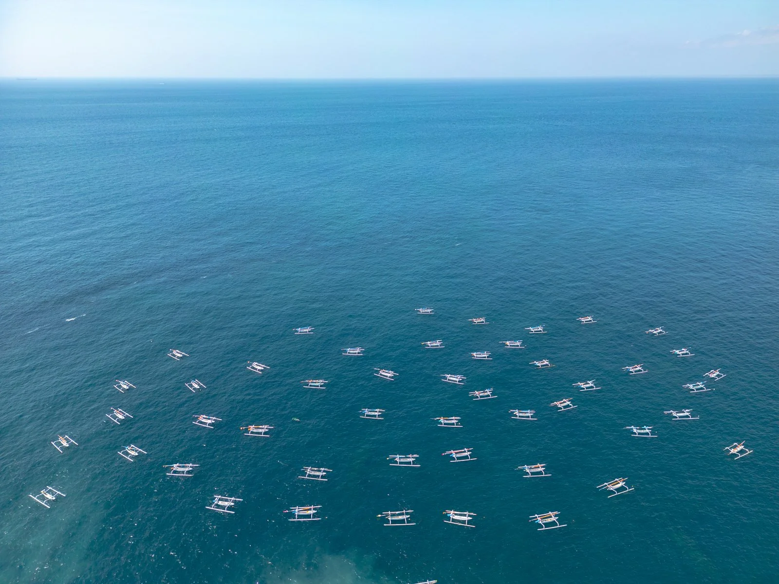 De nombreux bateaux flotter sur une large mer bleue, vue aérienne.