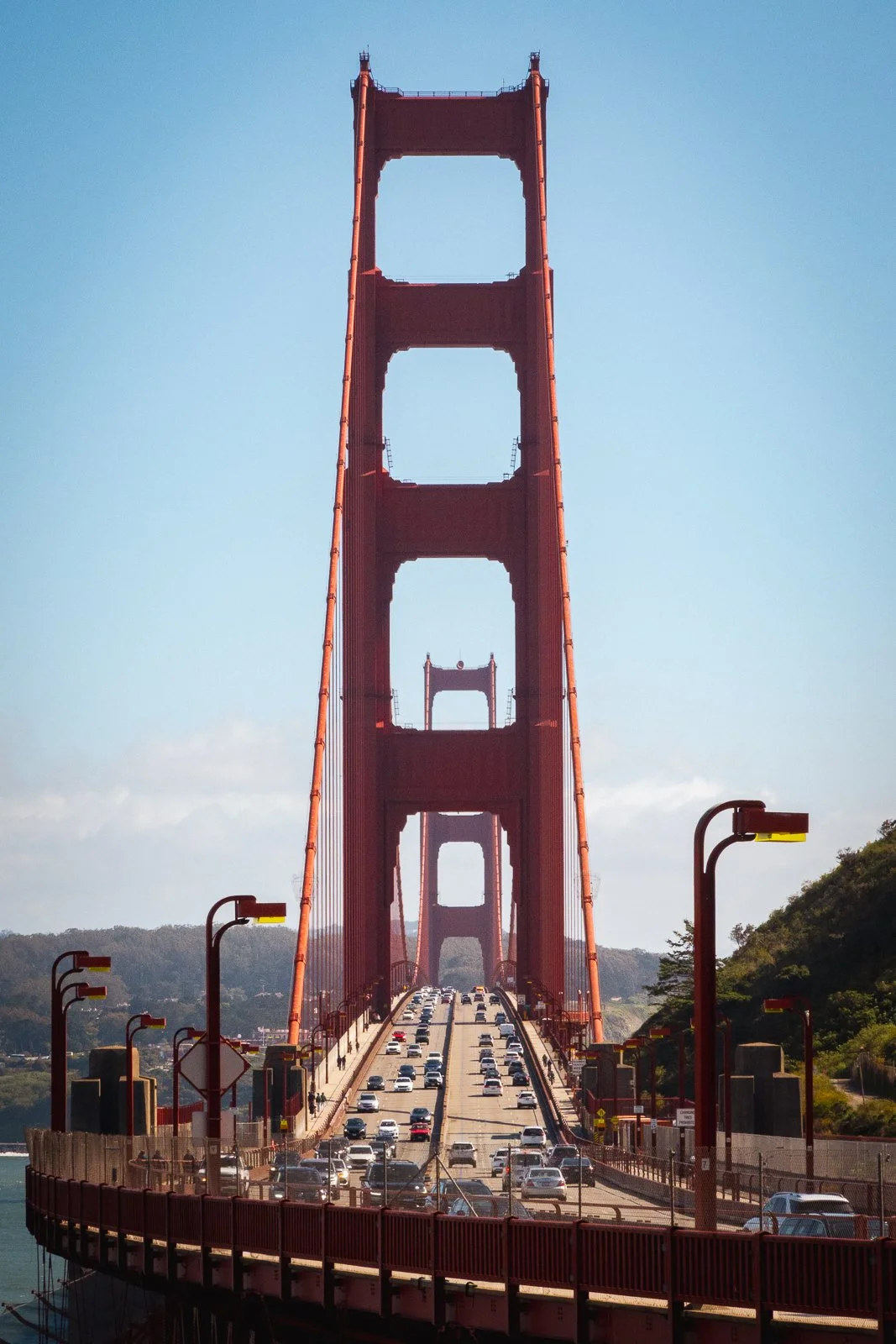 Pont suspendu de Golden Gate rouge avec beaucoup de voitures, sous un ciel clair avec peu de nuages.