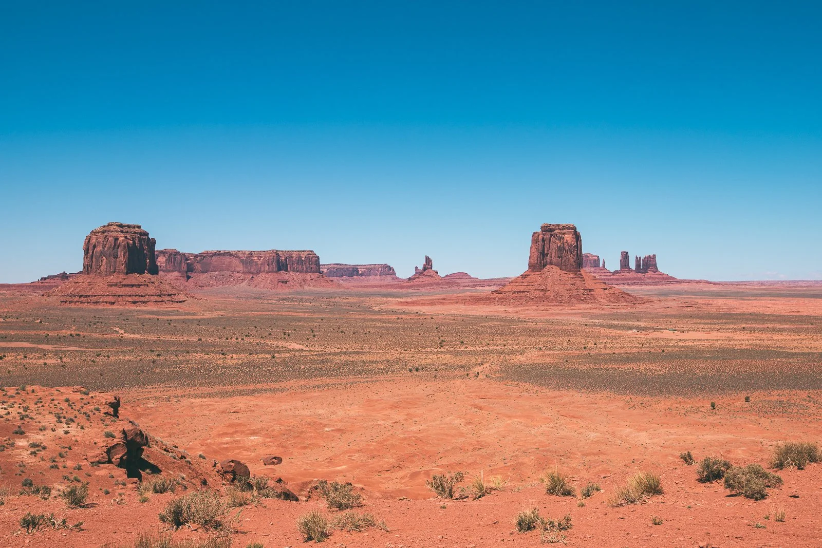 Paysage désertique avec formations rocheuses Monument Valley sous un ciel bleu clair.