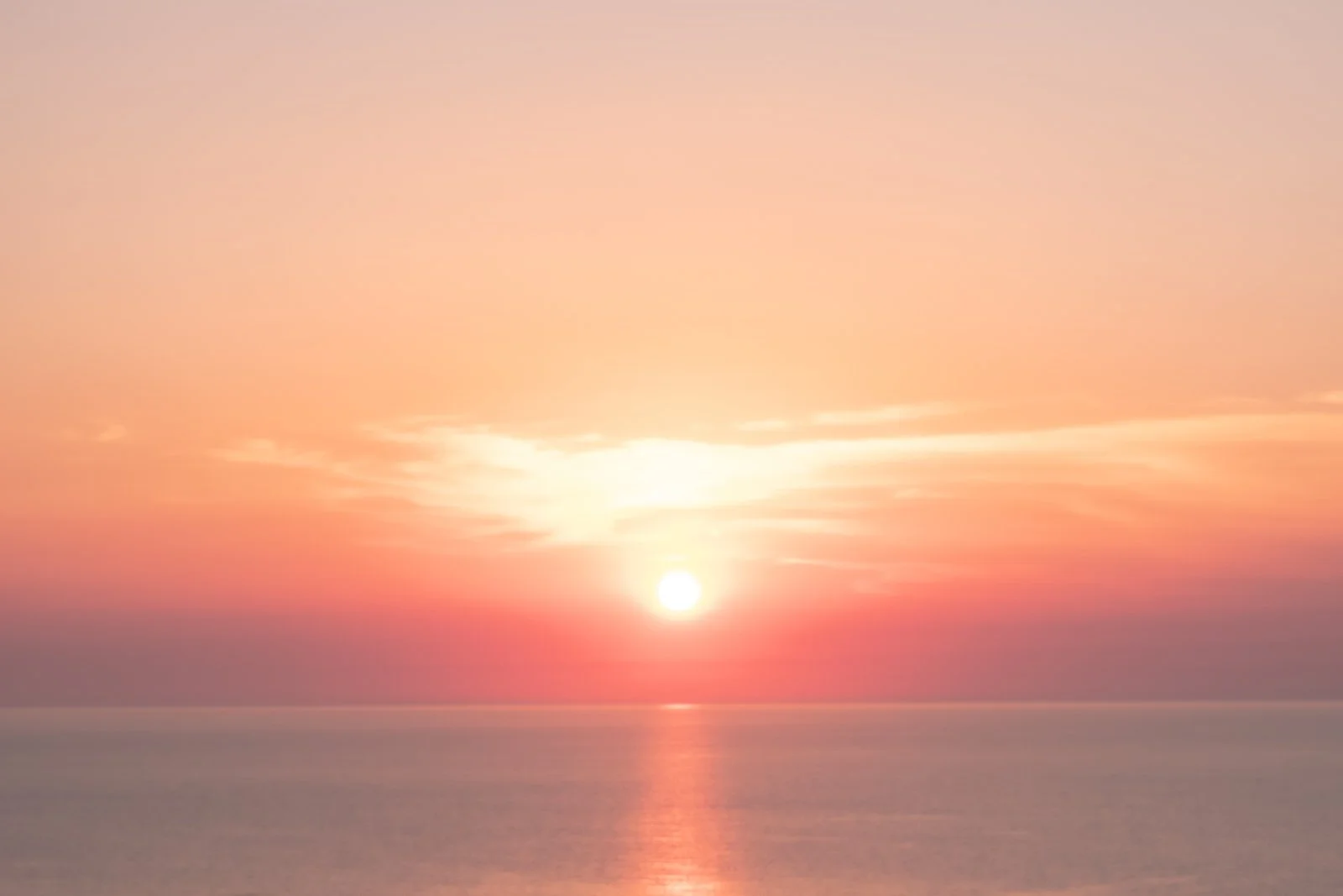 Coucher de soleil sur la mer avec un ciel pastel rose et orange