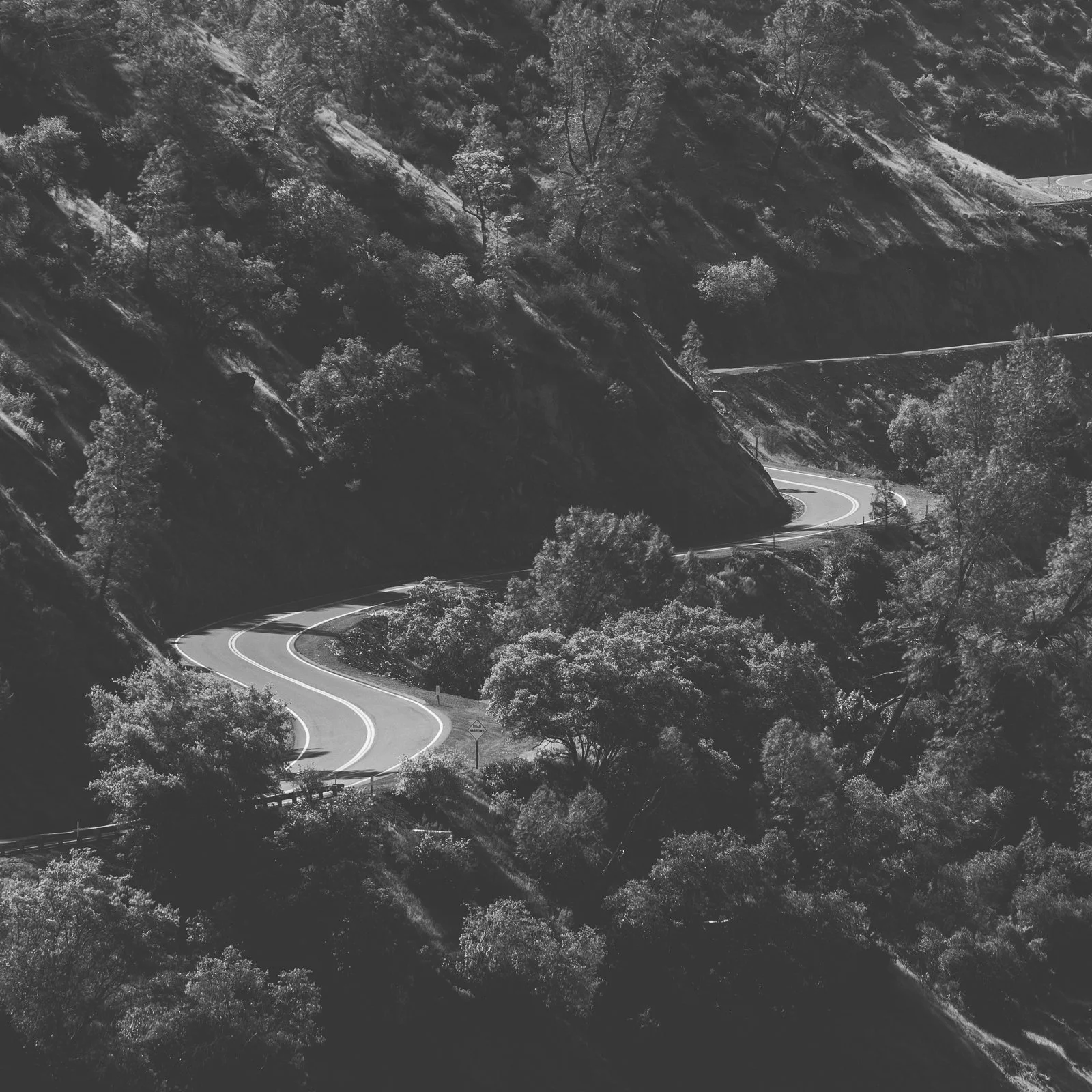 Une route sinueuse traversant une vallée montagneuse boisée.