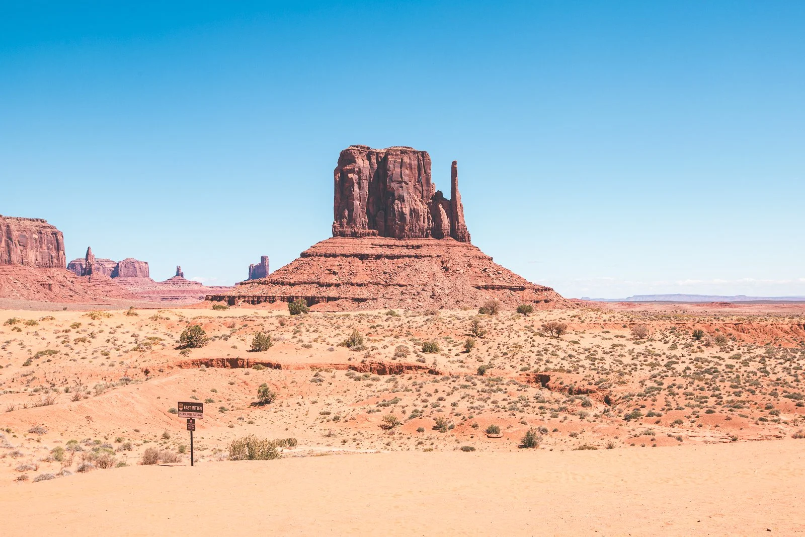 Paysage désertique avec des formations rocheuses rouges sous un ciel bleu clair.