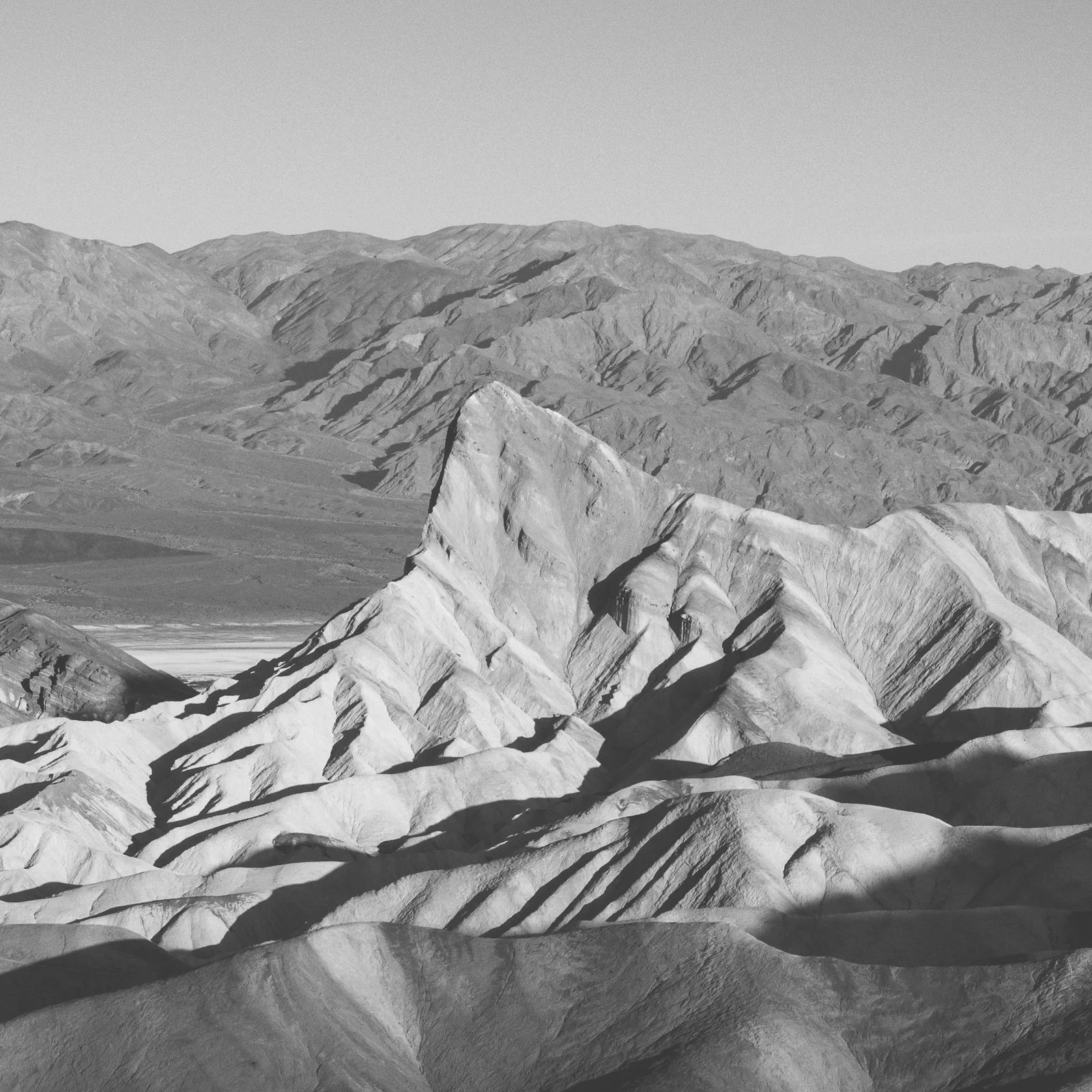 Montagnes rocheuses en noir et blanc avec des formationsagetiques et des ombres accentuées, paysage désertique.