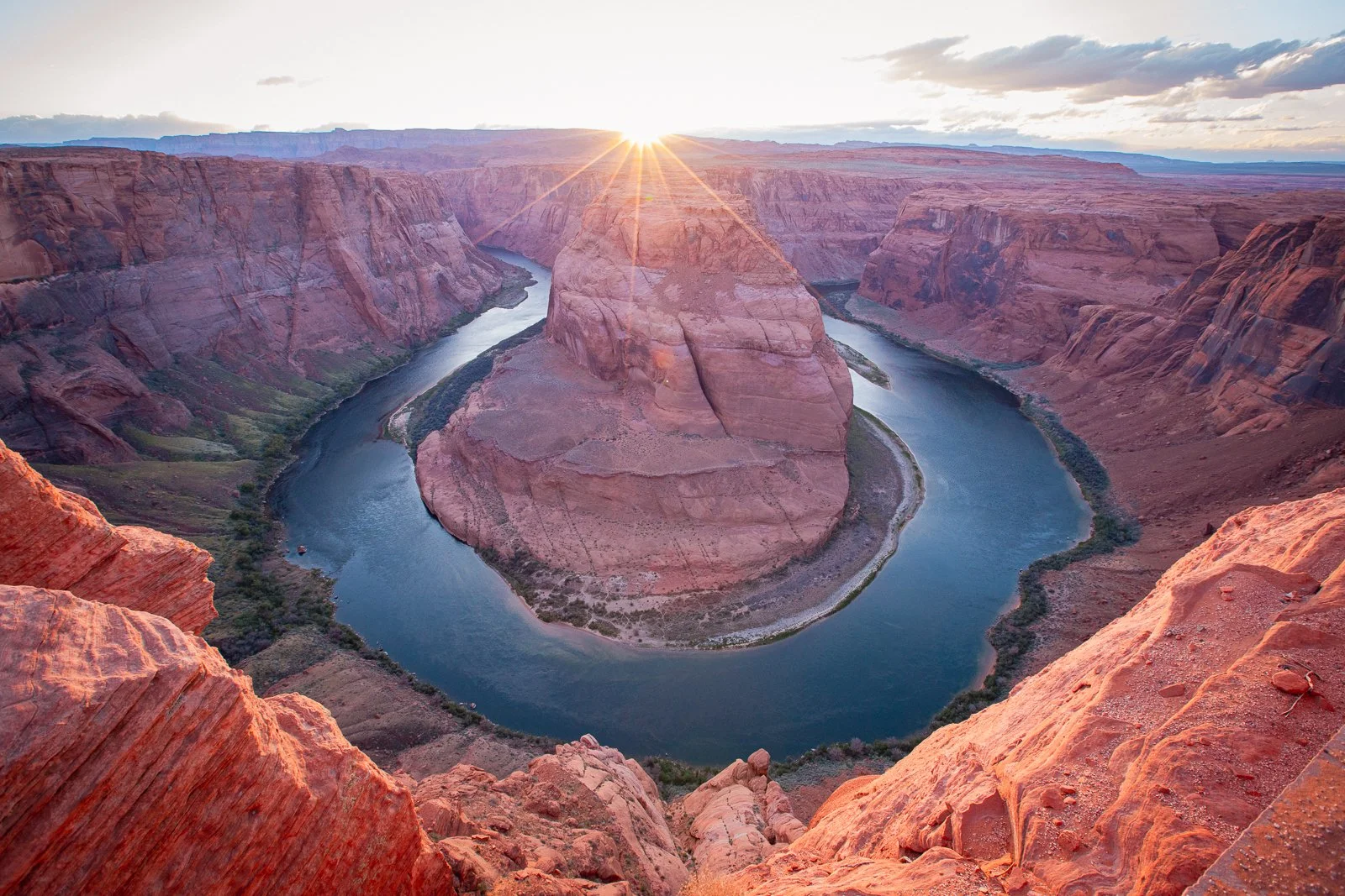 Canyon du Colorado avec une formation rocheuse au centre entourée par une rivière en forme de boucle, au coucher de soleil.