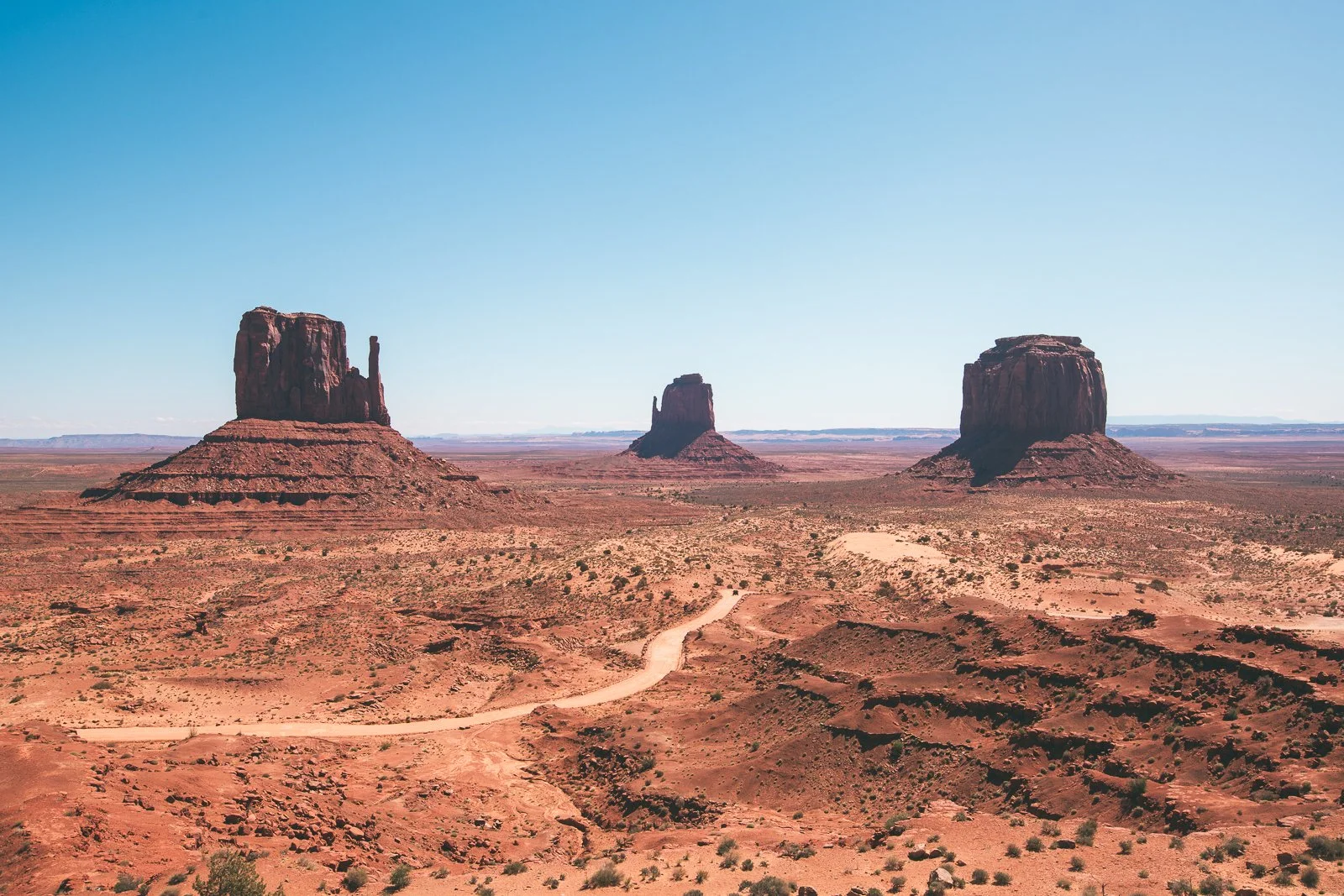 Trois buttes rocheuses dans un désert avec un ciel clair.