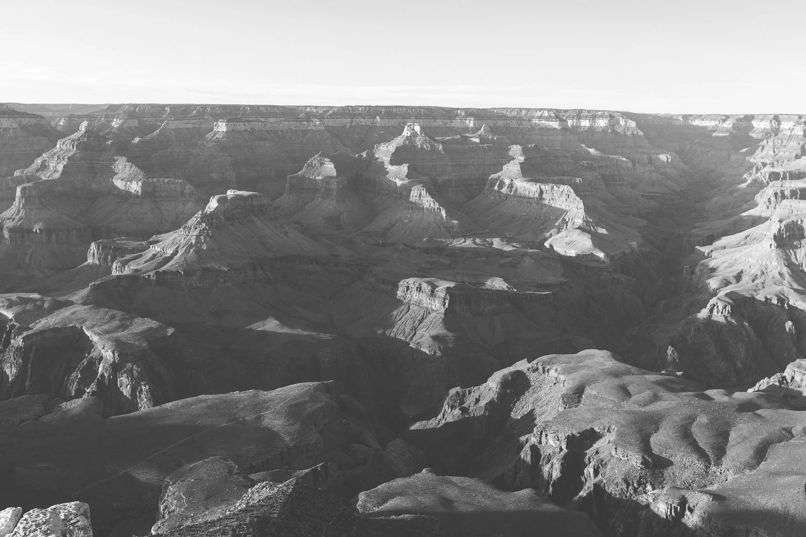 Photographie en noir et blanc du Grand Canyon montrant ses formations rocheuses et ses profondes vallées.