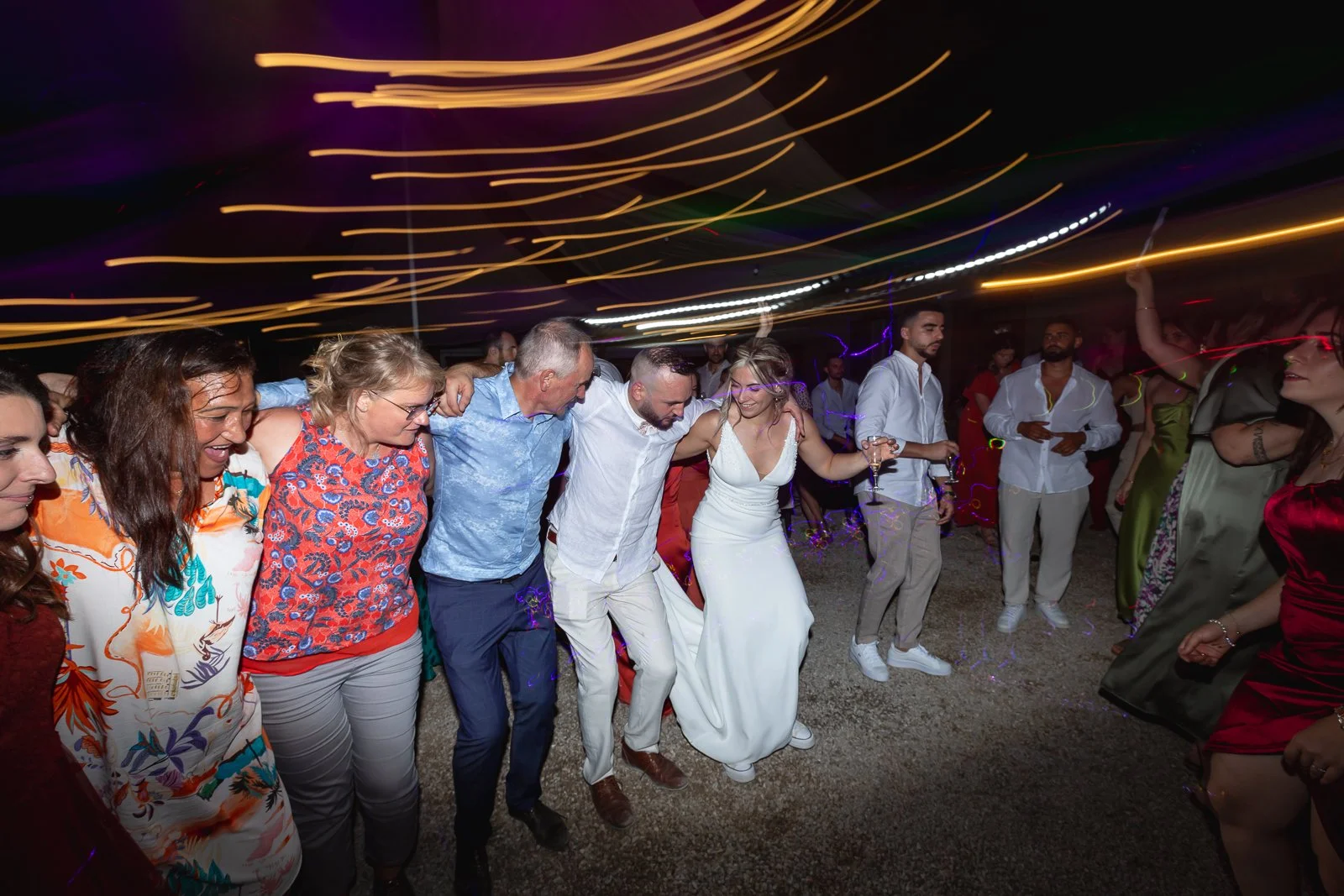 Groupe de personnes dansant lors d'une fête ou d'un mariage, sous des lumières colorées