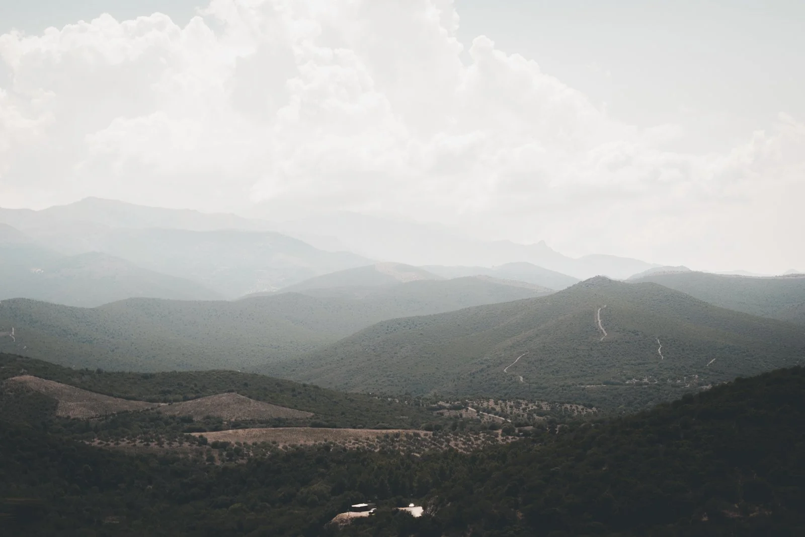 Paysage de montagnes avec des collines verdoyantes et un ciel nuageux.
