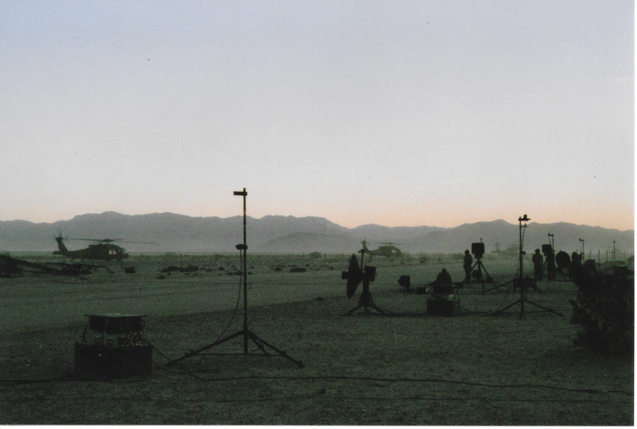 Footage of helicopters and filming equipment on set during dusk, with mountains in the background.