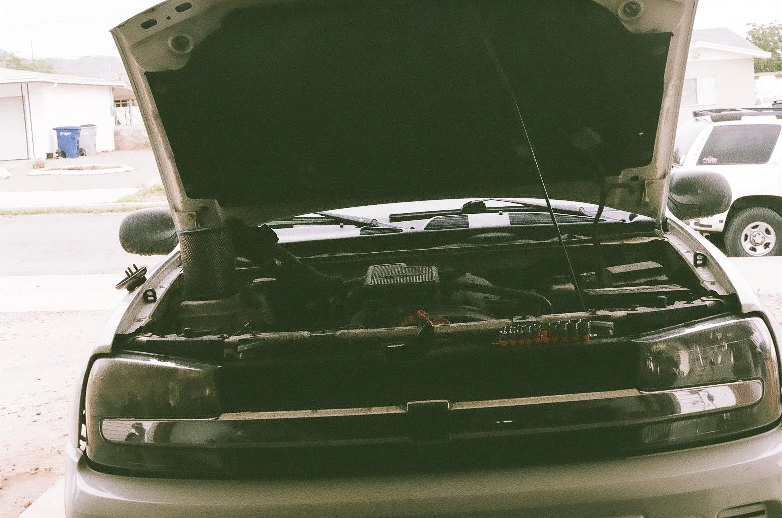 Front of a car with its hood open, showing the engine compartment.