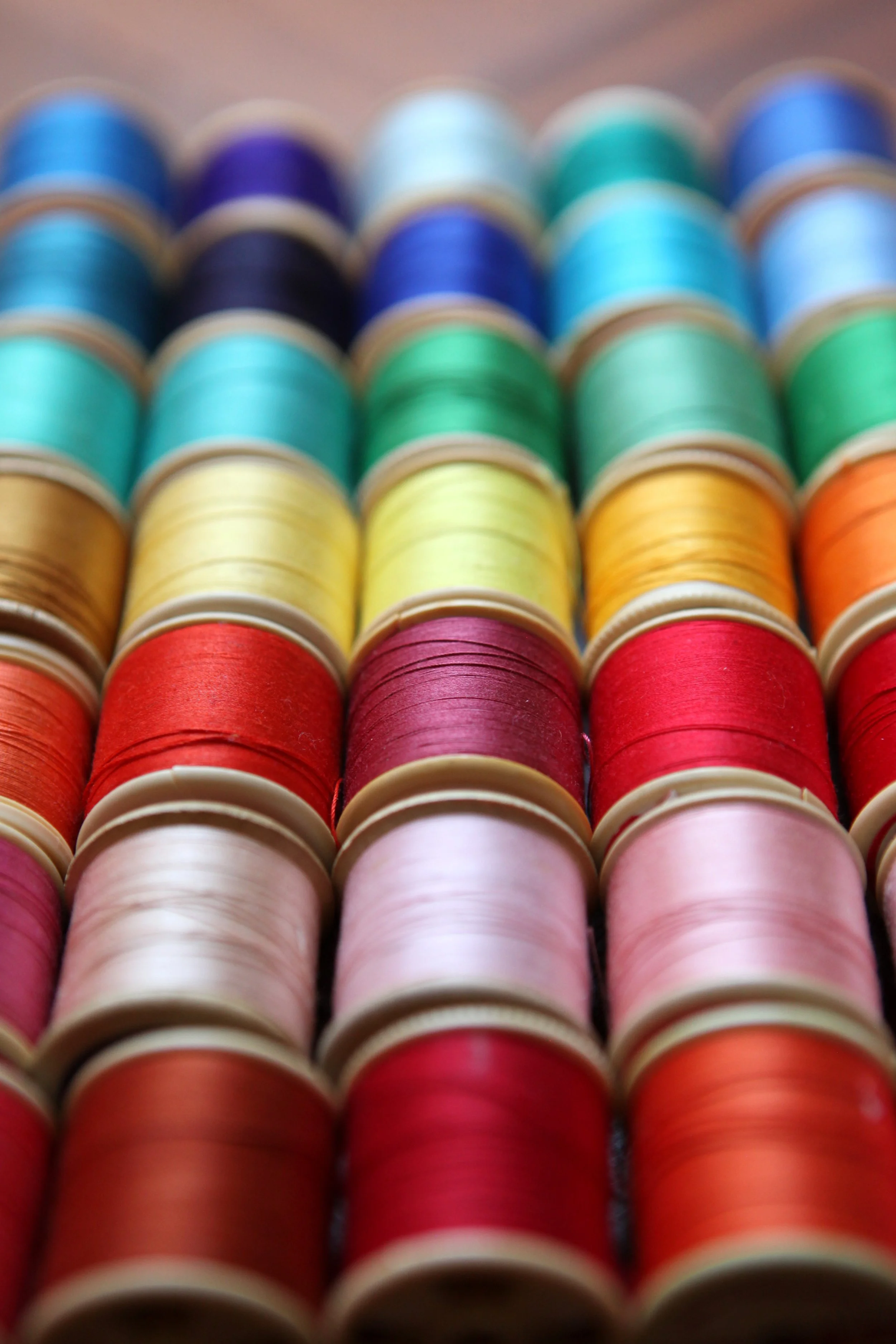 Close-up of rows of colorful sewing thread spools arranged in a grid.