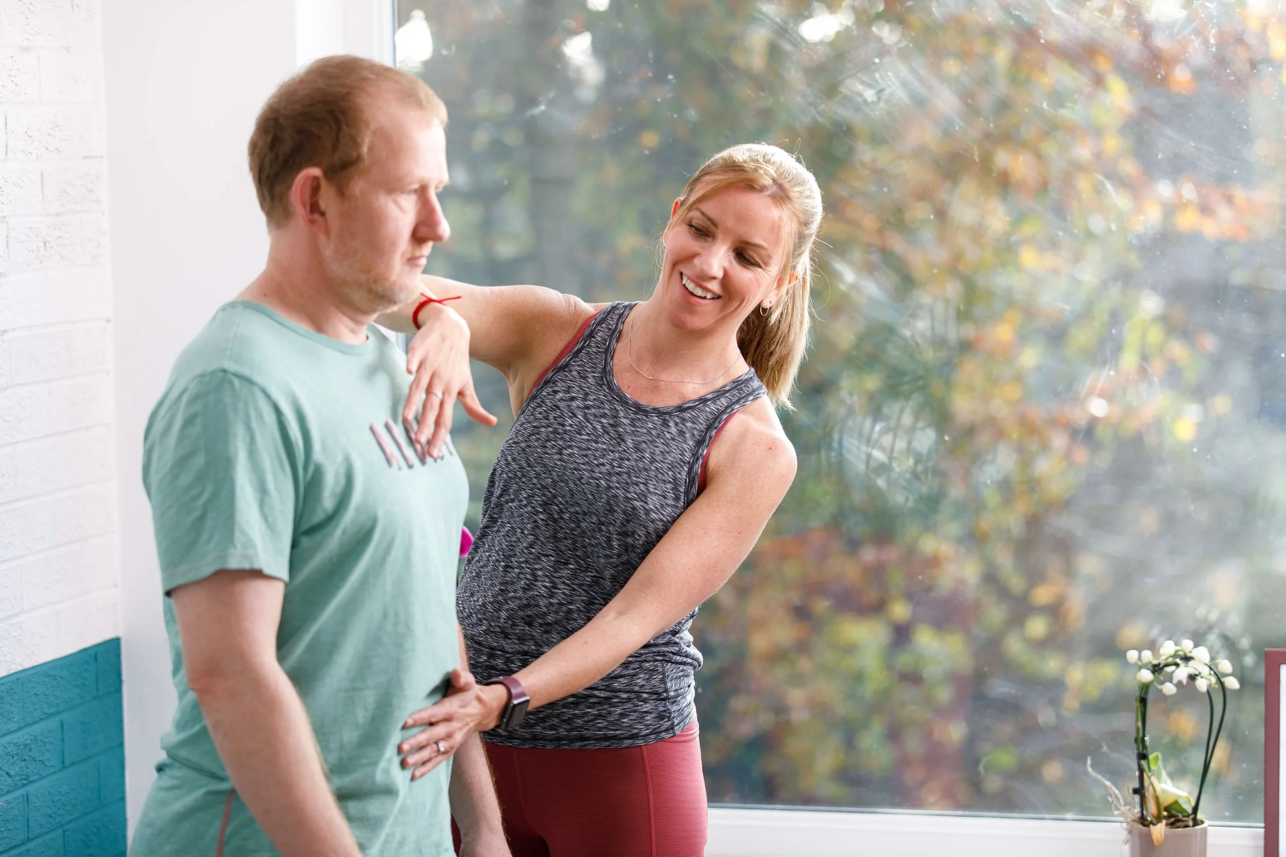 Louisa, founder at Move Well Studio helps a male student during a pilates class